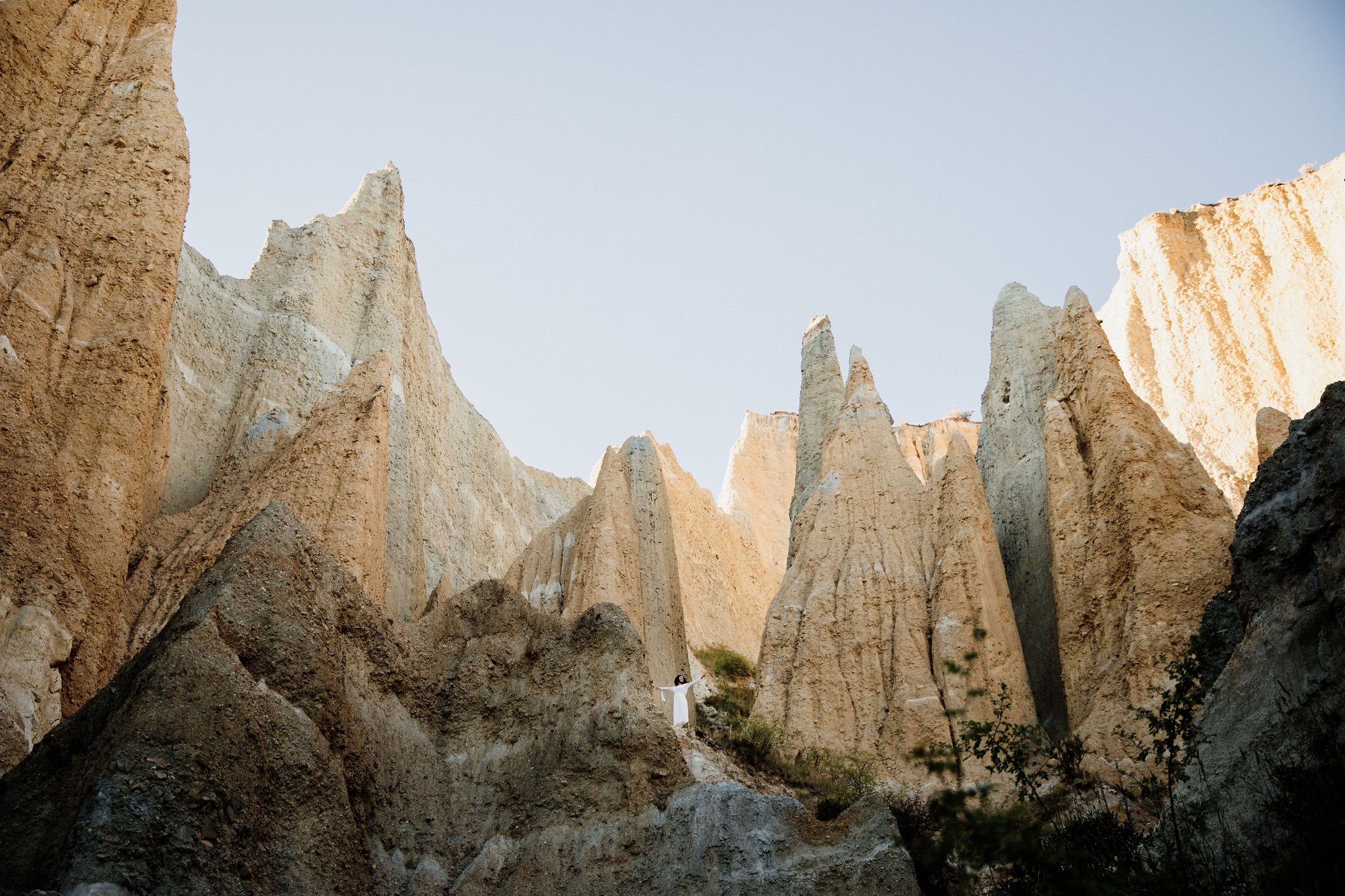 Figure standing among sculptural rock formations in a dramatic natural landscape.