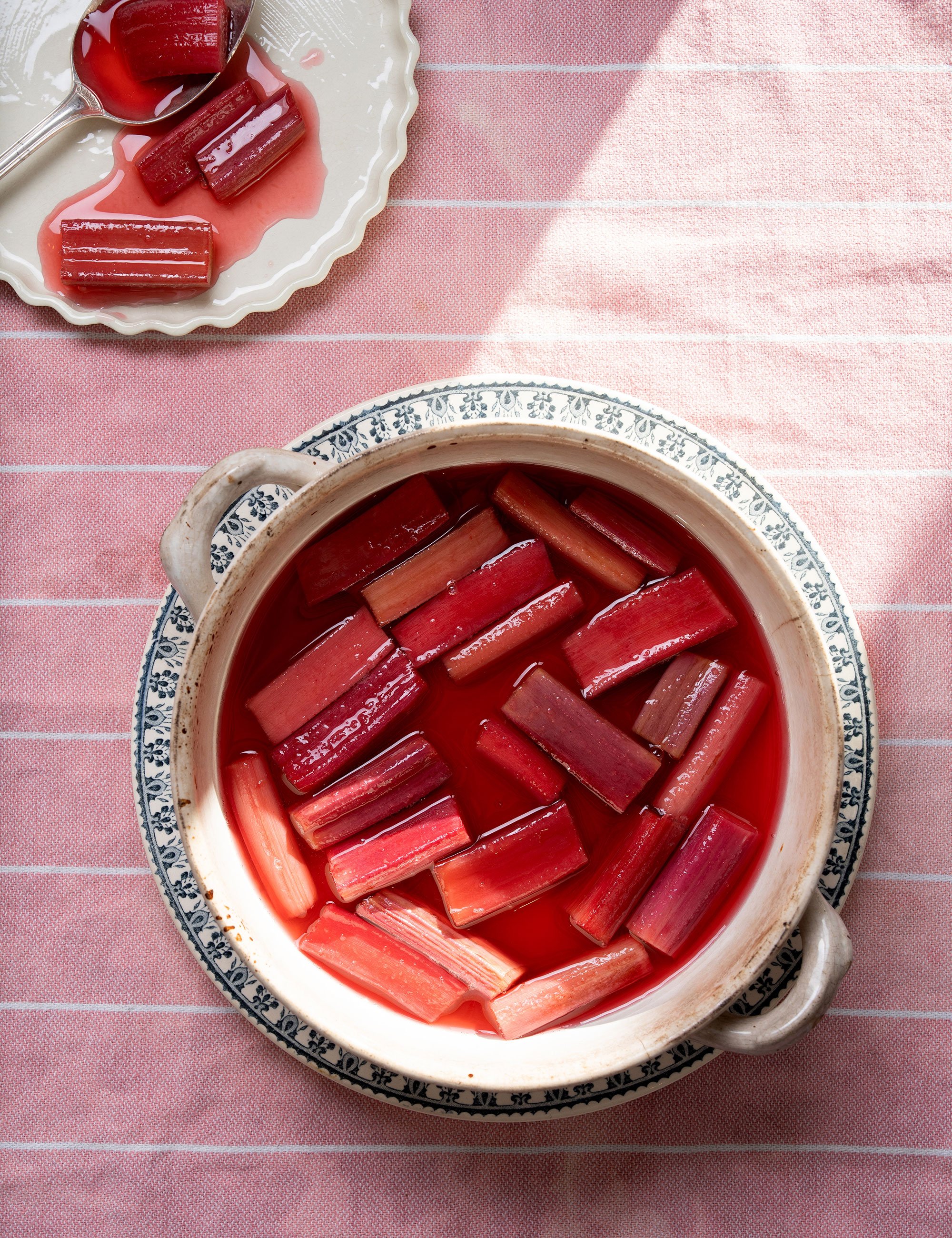 Jar of preserved rhubarb pieces photographed overhead on a pink cloth.