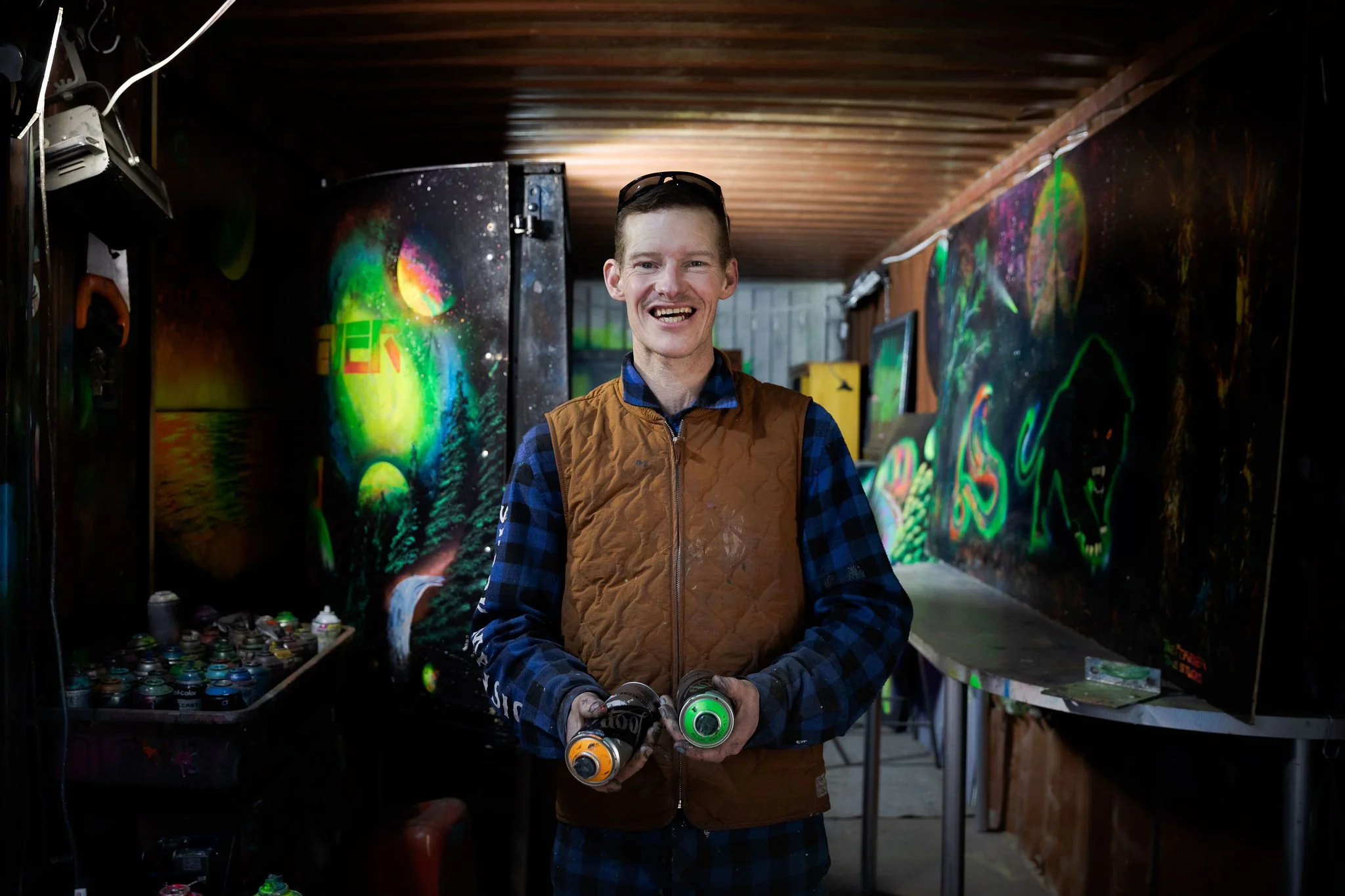 Artist portrait of Philip Currie standing in a colorful workshop or studio space.