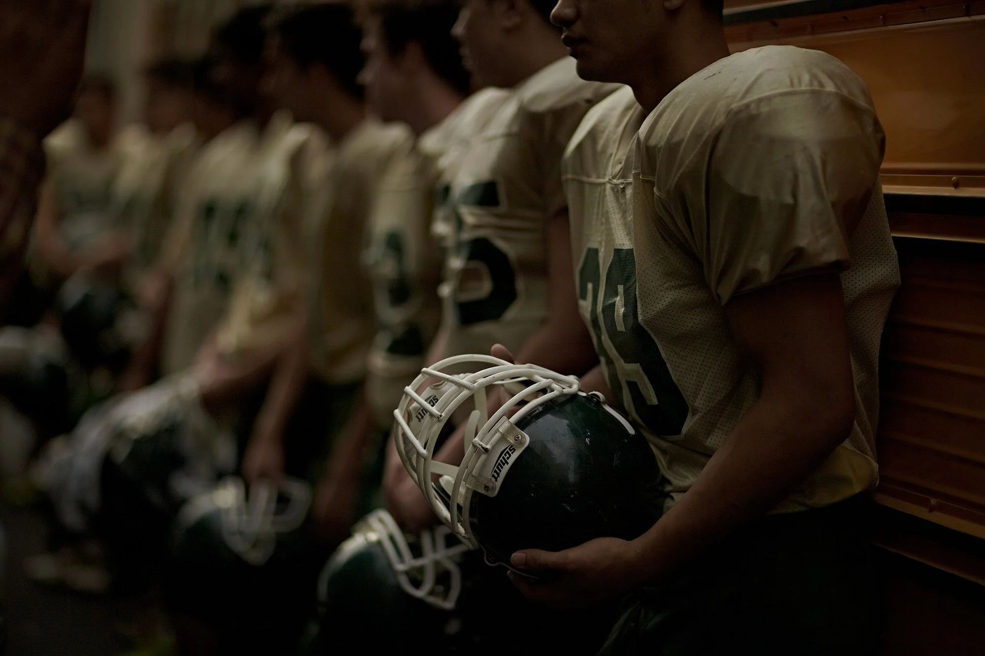 Documentary-style sports photography showing the quiet tension and anticipation of a football team before competition.