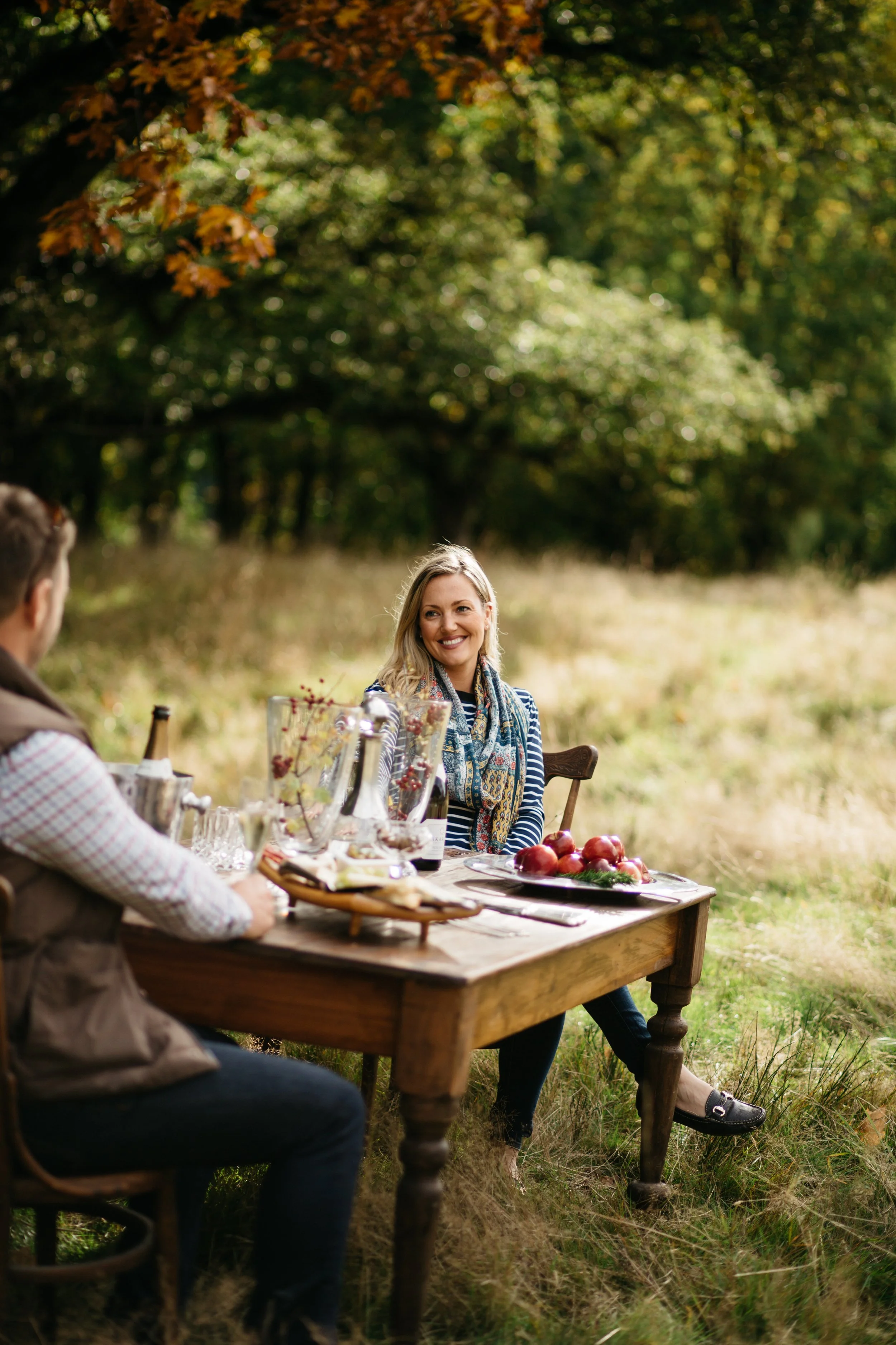 Guests enjoying an outdoor picnic table experience in a garden setting for a New Zealand tourism campaign.