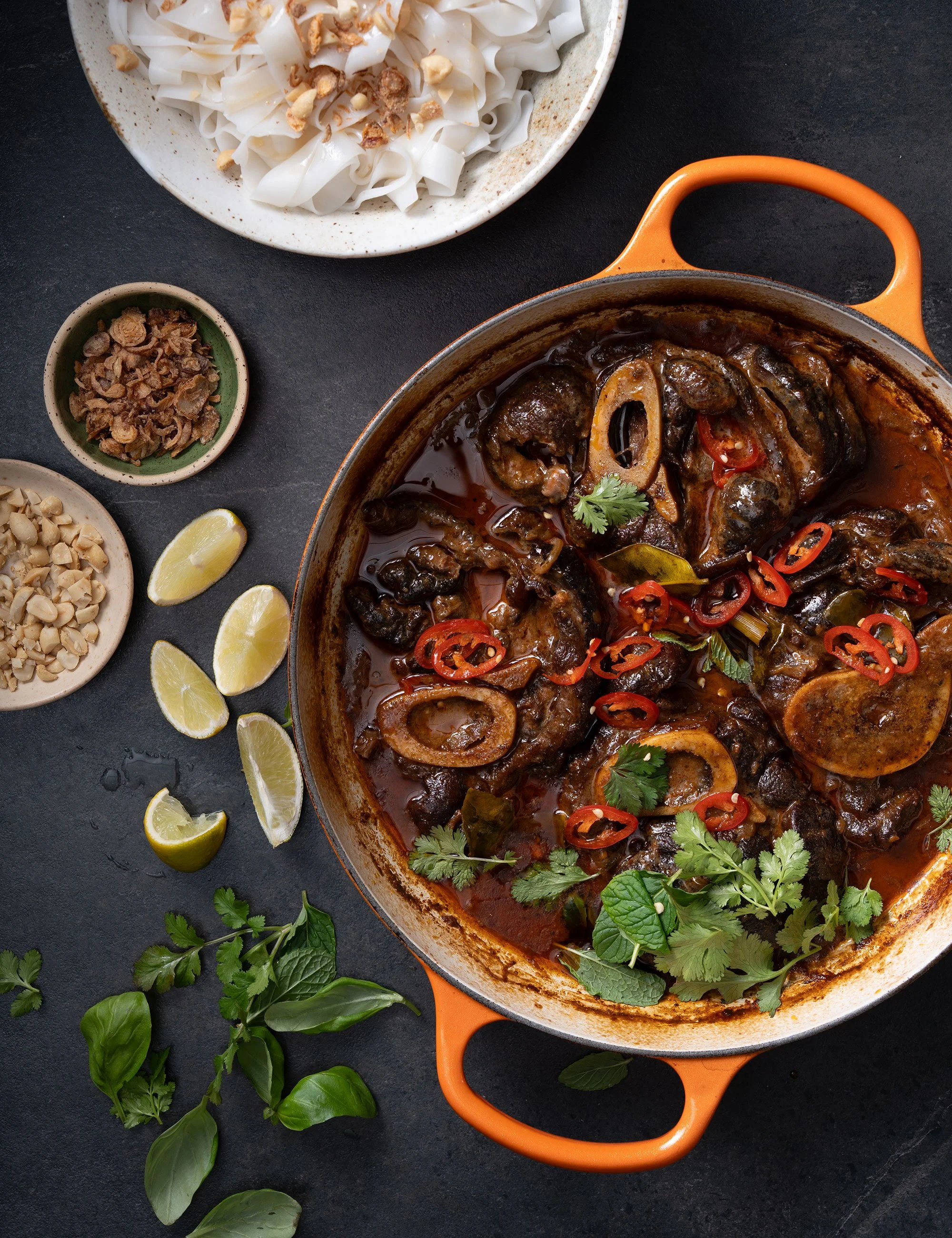 Orange casserole dish of cooked prawns or seafood served with sides.