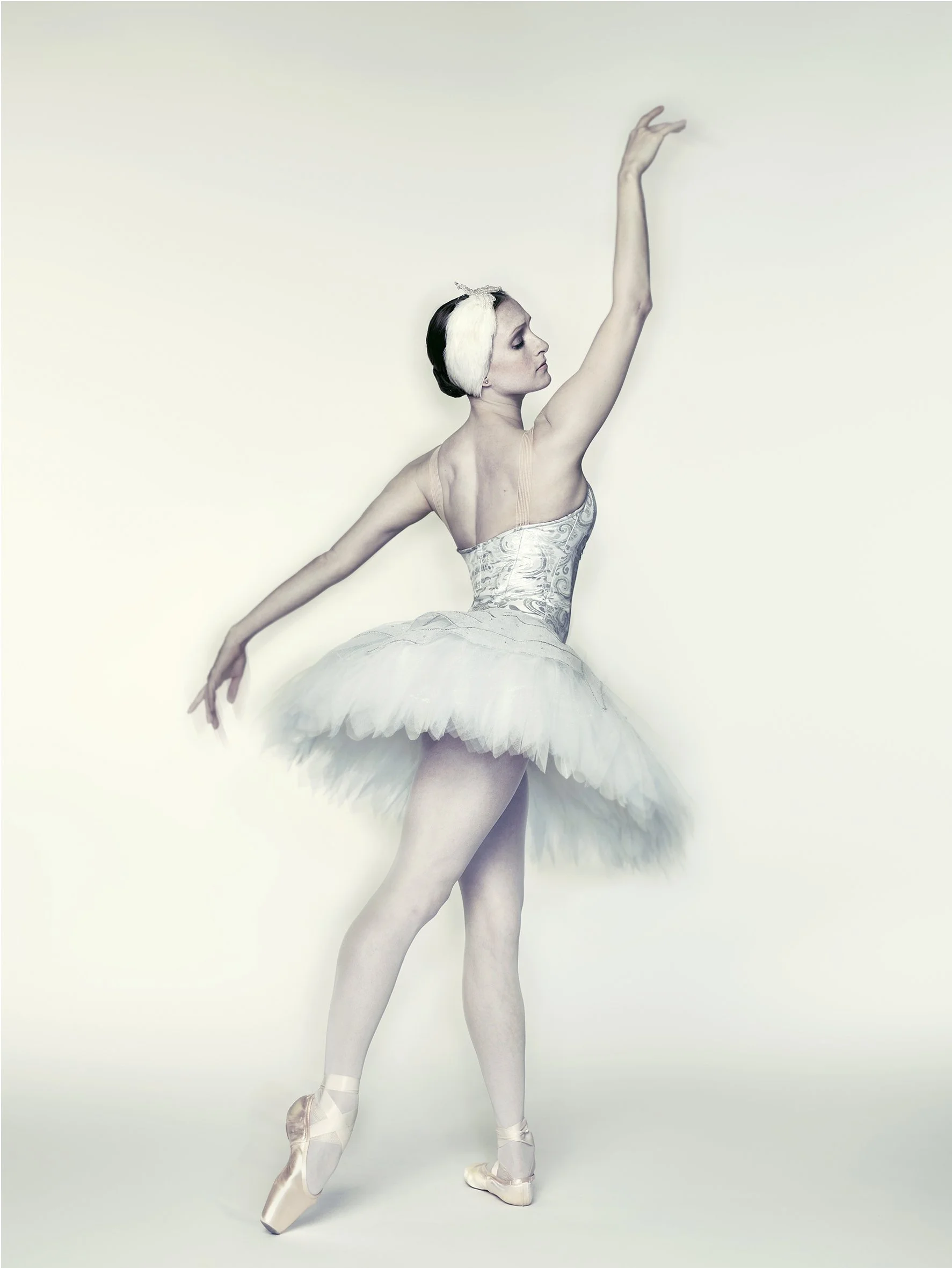Classic ballet portrait photographed with a soft, ethereal treatment and a clean, minimal studio composition.