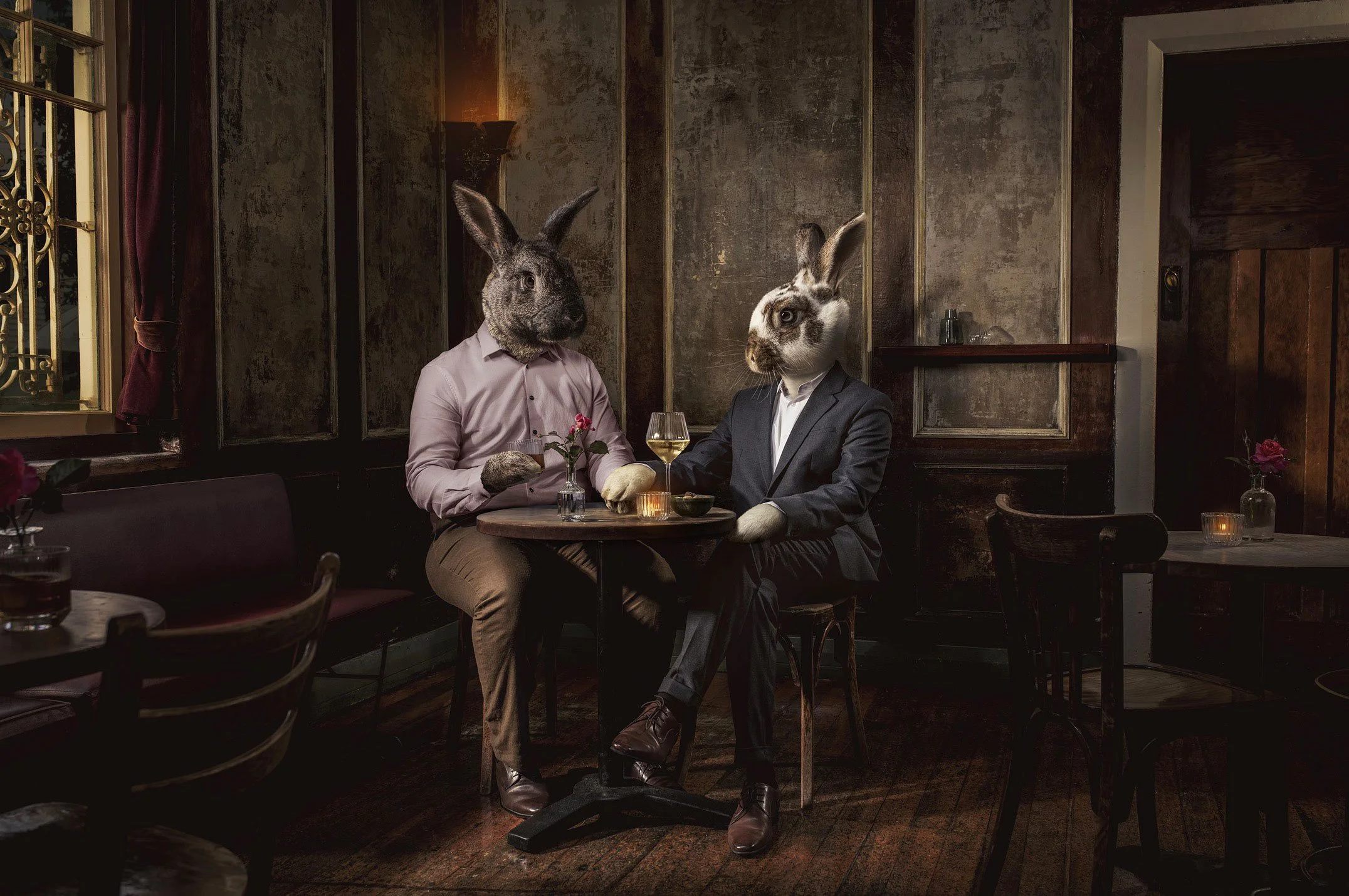 Conceptual portrait of two rabbit-headed characters for a  sharing a quiet moment in a moody restaurant setting photographed  for a Pharma campaign.  