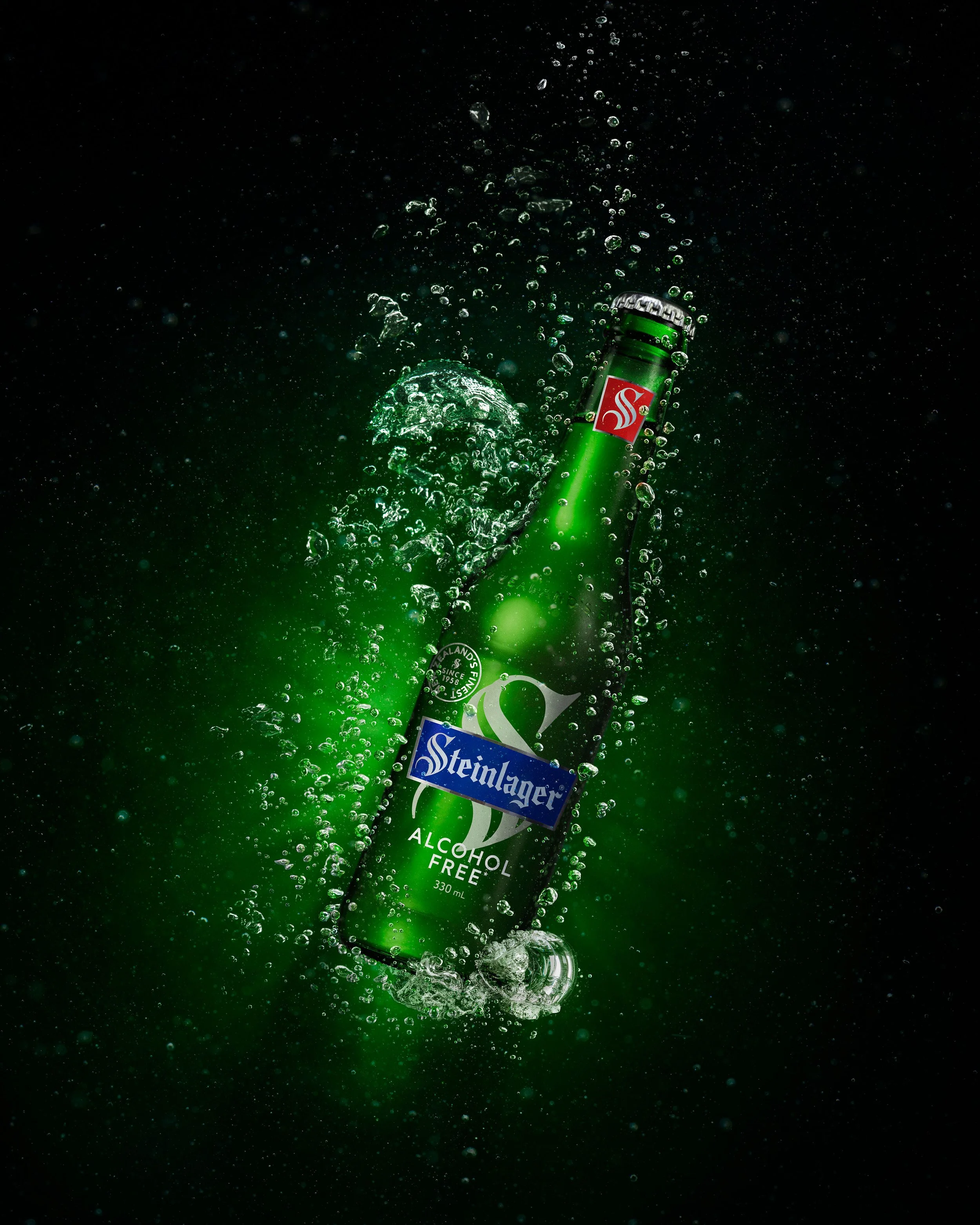 Dynamic product image of Steinlager Classic with underwater-style bubbles and glowing green light, emphasizing refreshment and energy.