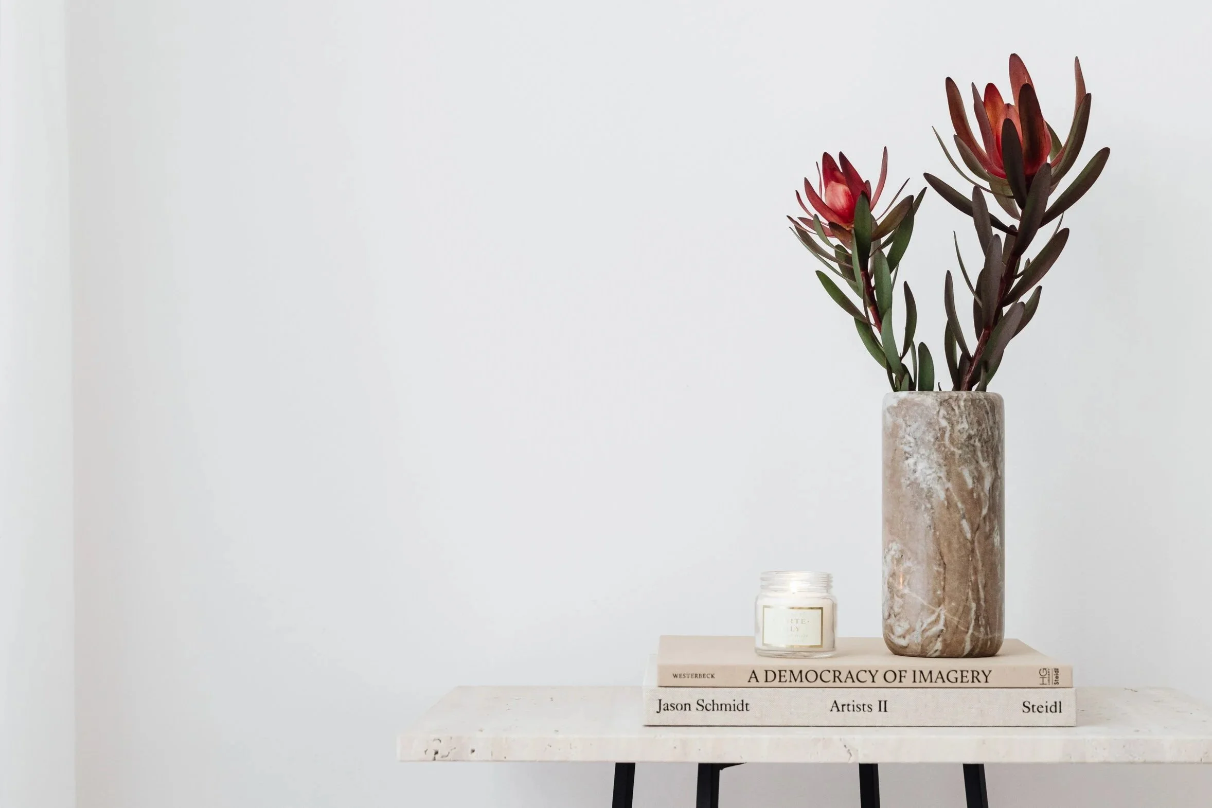 Clean, organised counter with red flowers in a stone vase stacked on books