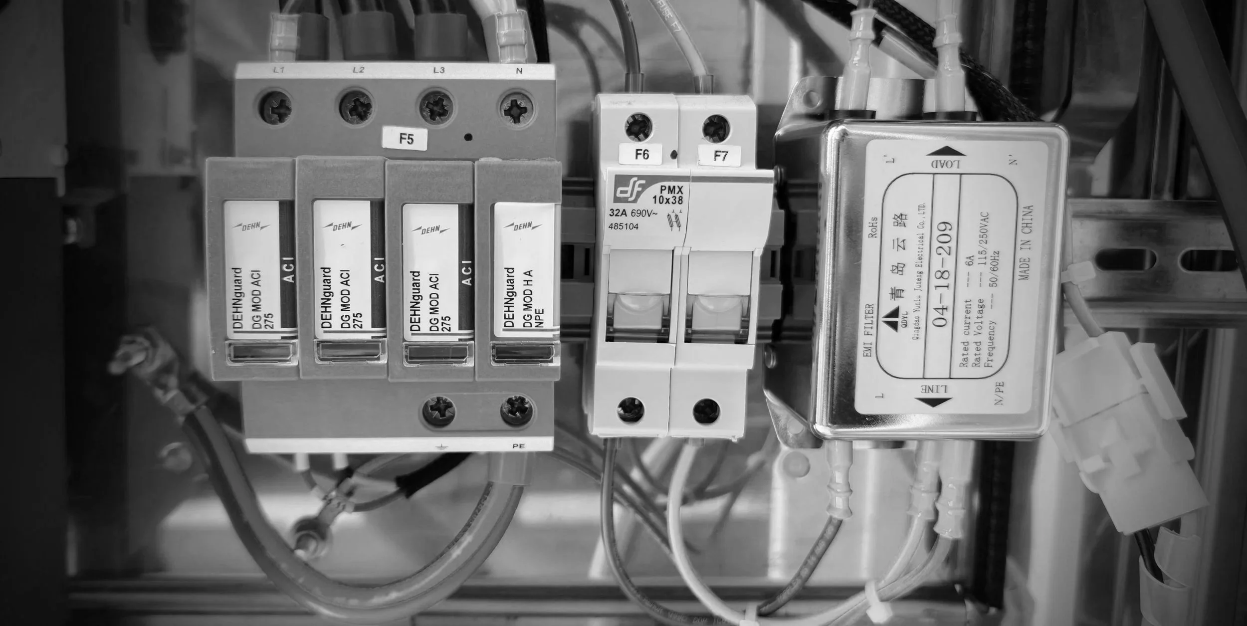 Close-up of electrical components within an industrial control panel, including fuses and circuit breakers labeled with technical specifications, wires, and connectors.