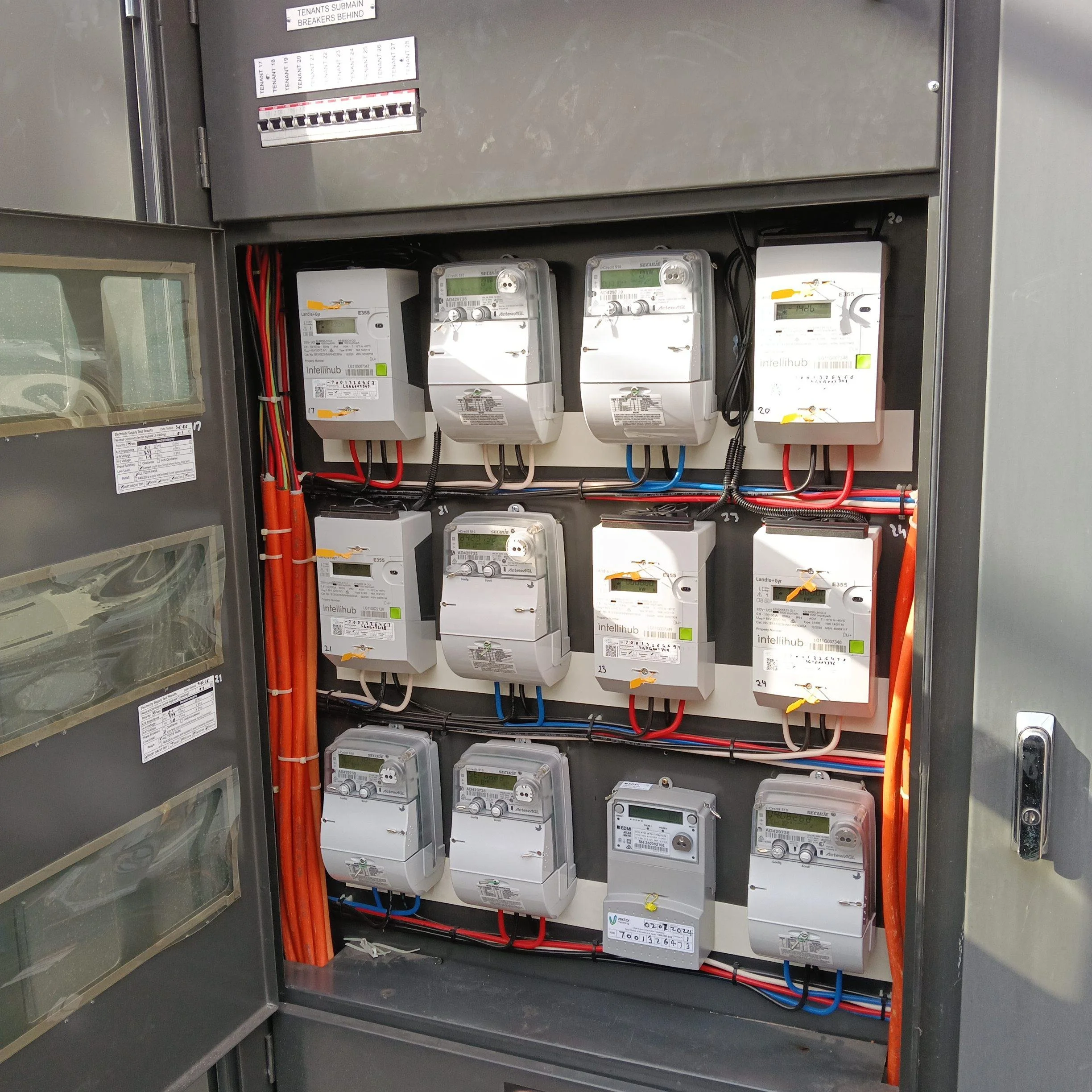 Electrical panel with multiple digital meters, circuit breakers, and wiring, labeled for tenant submain breakers.