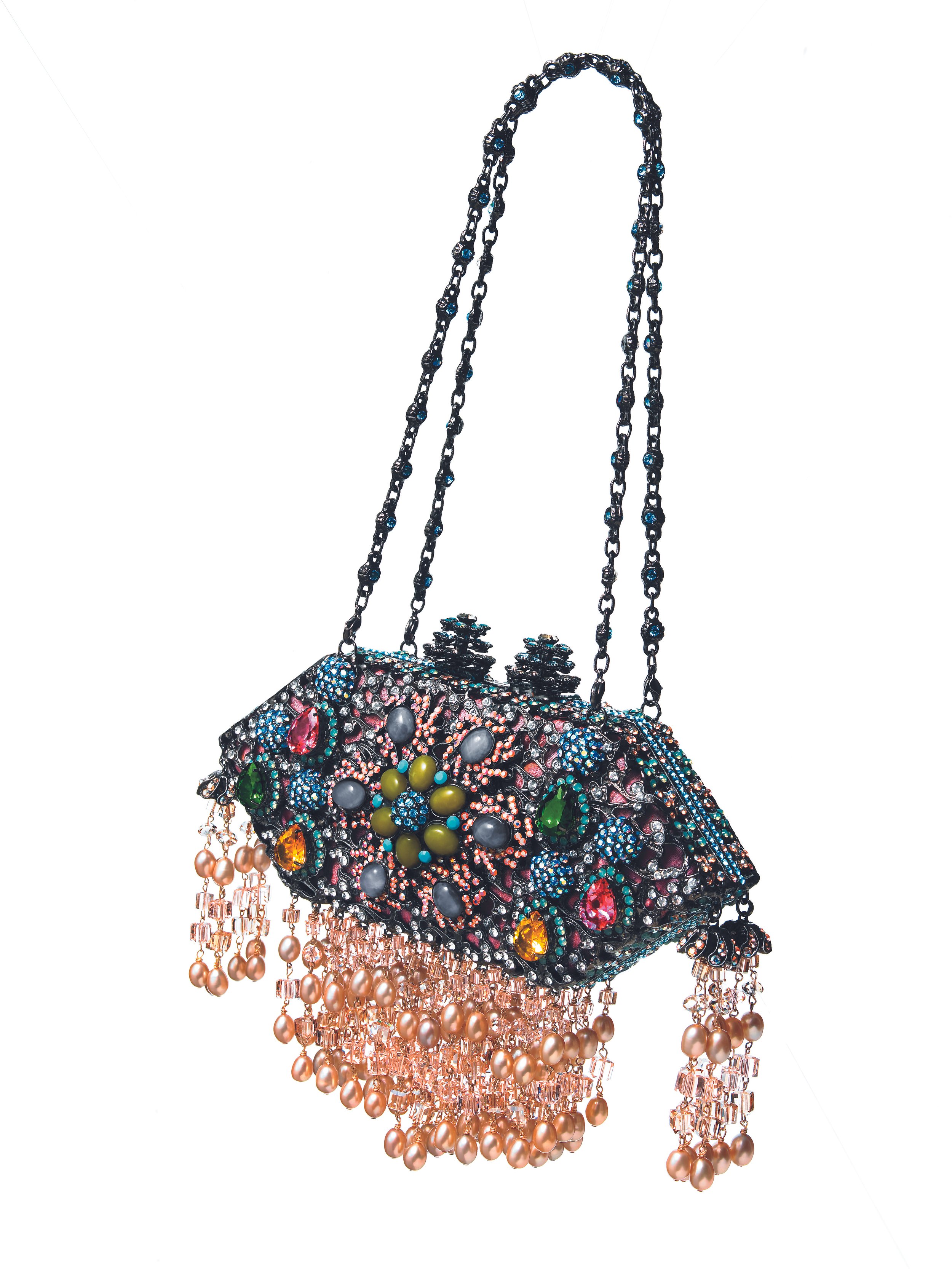 A decorative handbag covered in colorful gemstones and rhinestones, with pink pearl and crystal tassels hanging from the bottom.