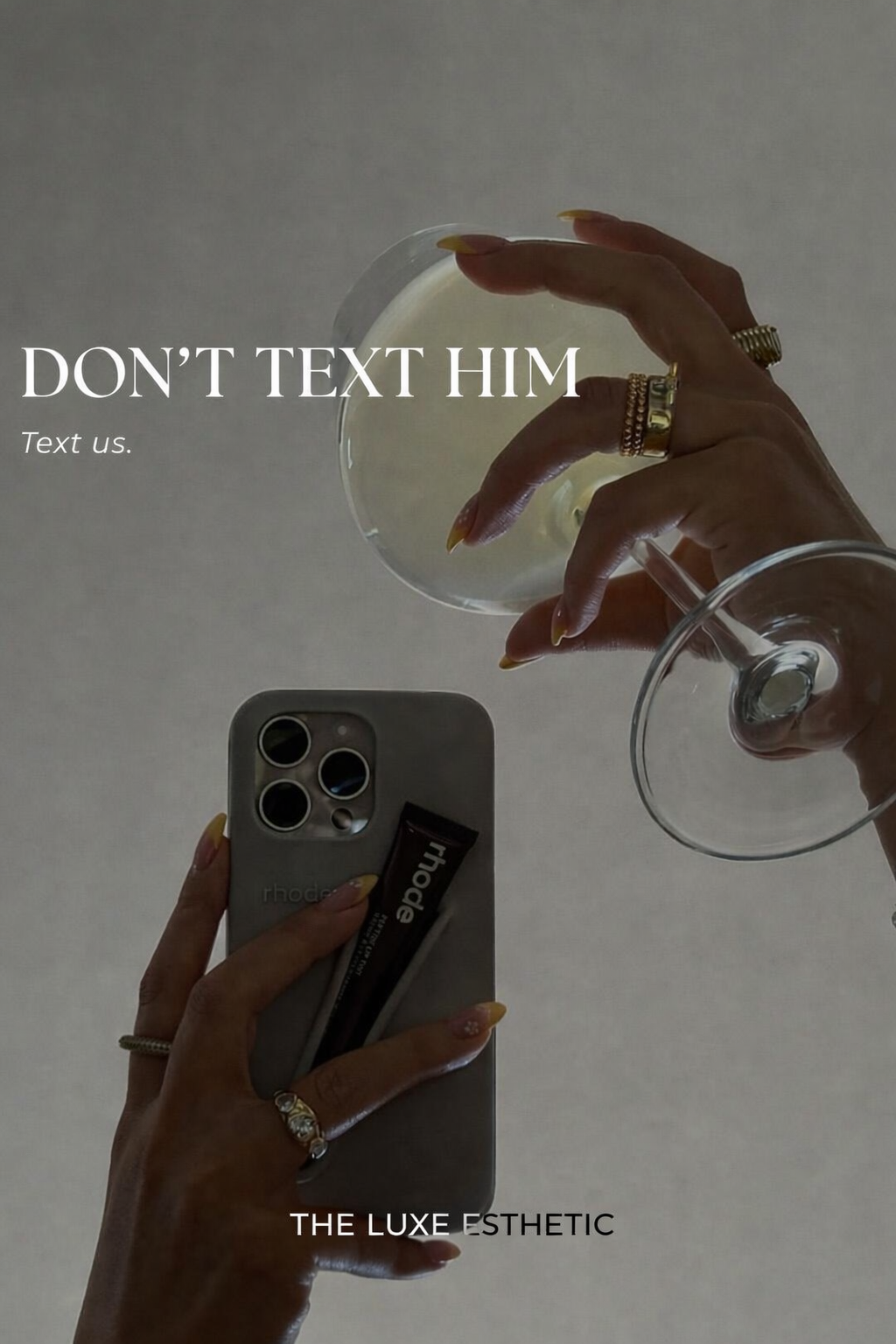 Close-up of a person's hand holding a smartphone and a glass of wine, with another hand holding a glass of wine. The person is wearing rings and has manicured nails. Text overlay: 'DON'T TEXT HIM. Text us. THE LUXE ESTHETIC'.