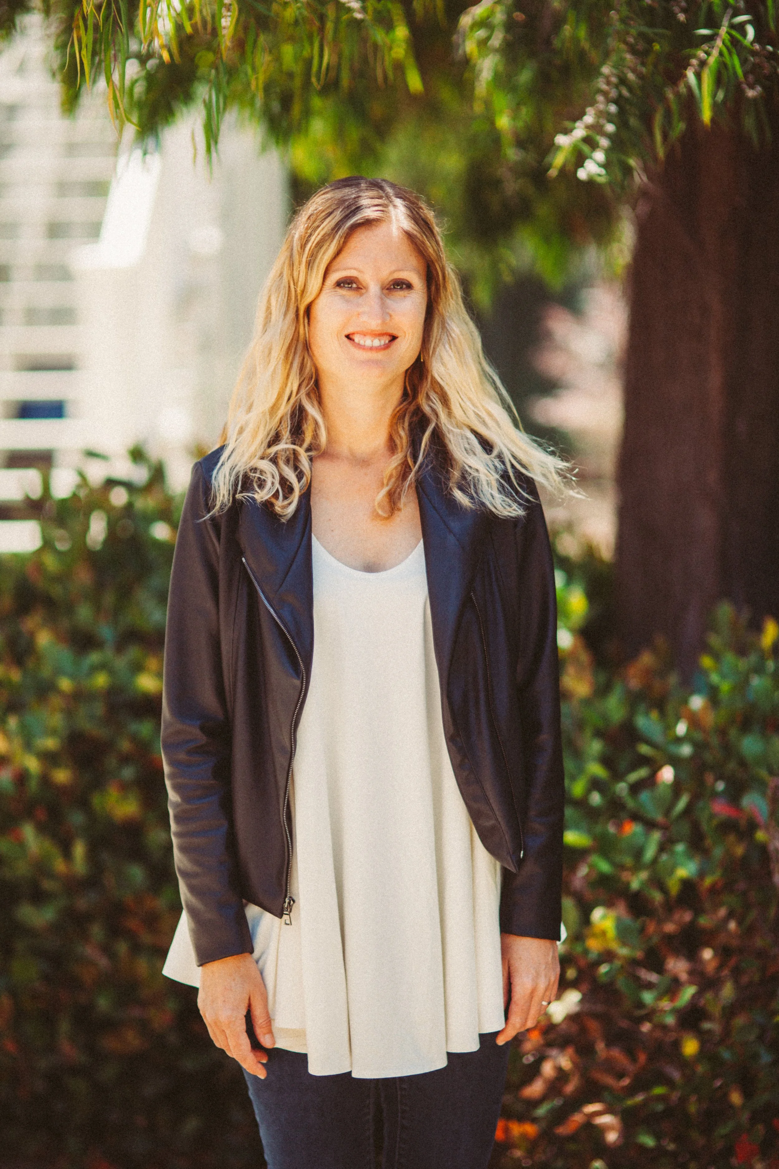 Emily Slater, Children's Ministry Director, smiling outdoors in a denim jacket with trees in the background