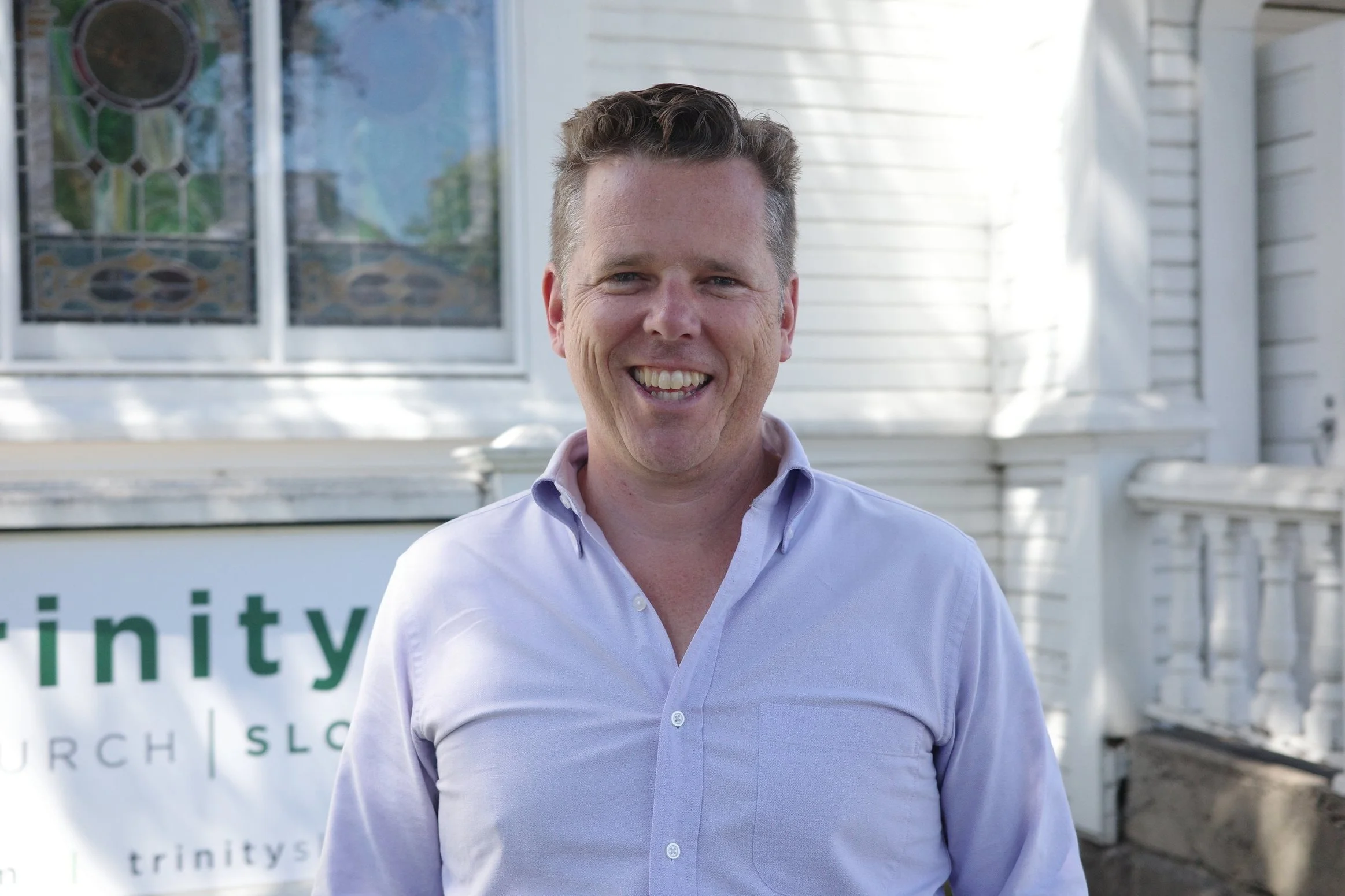 Bryce Hales, Pastor, smiling outdoors in a lavender button-up shirt