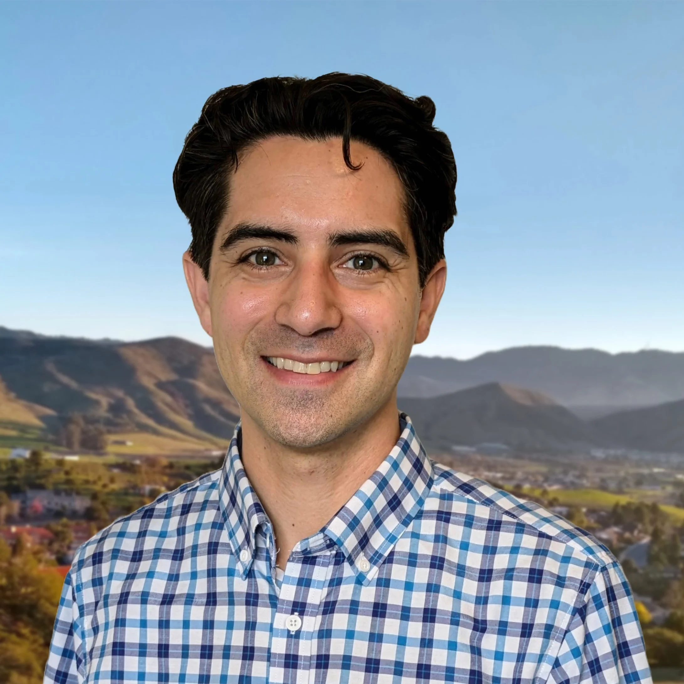 Lucas Centeio, Director of Sunday Operations, smiling outdoors with rolling hills behind him