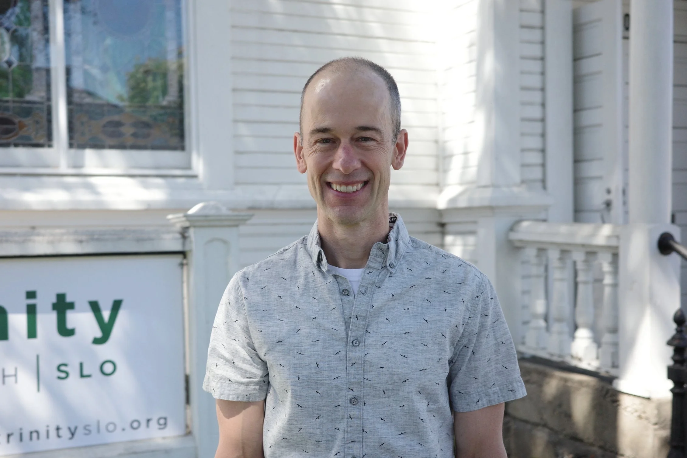 Mike Heying, elder, smiling outdoors in a gray patterned shirt