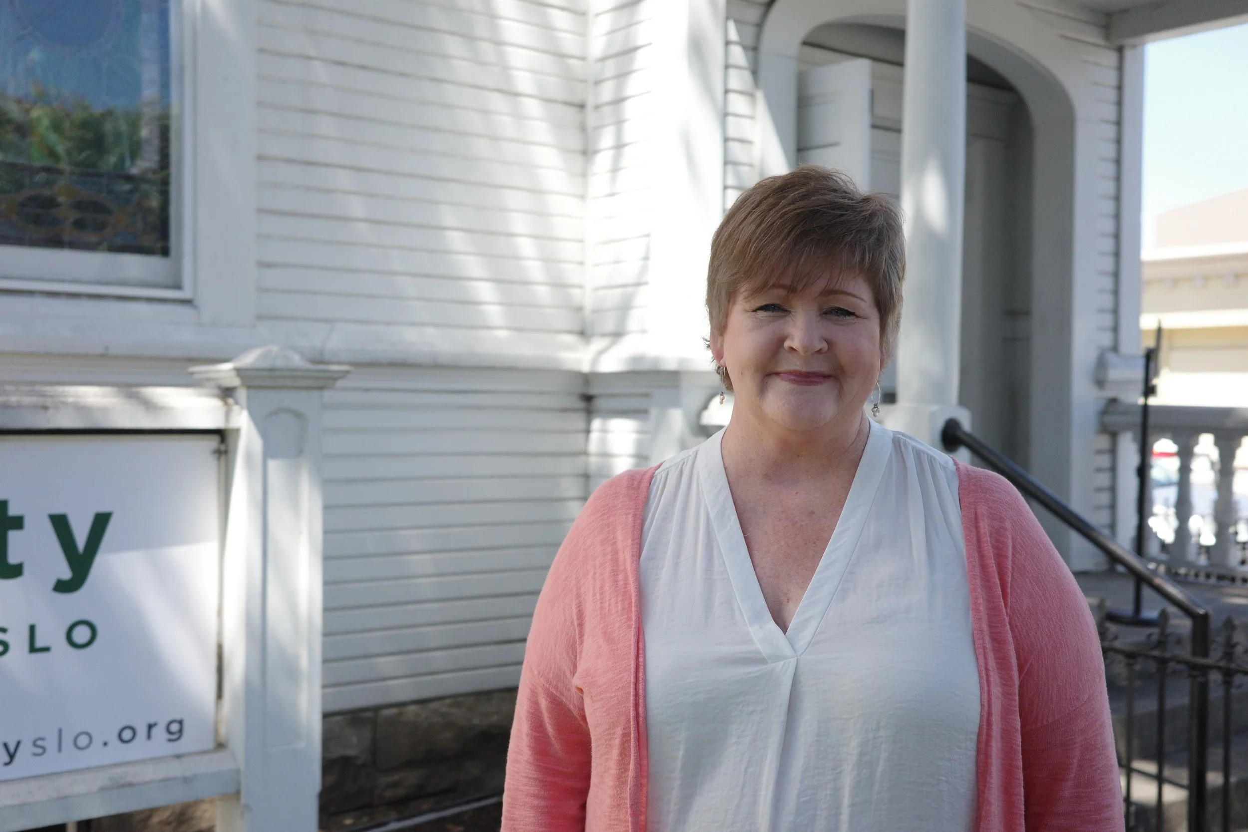 Colleen Wall, Mercy Team, smiling outdoors in a white top and pink cardigan