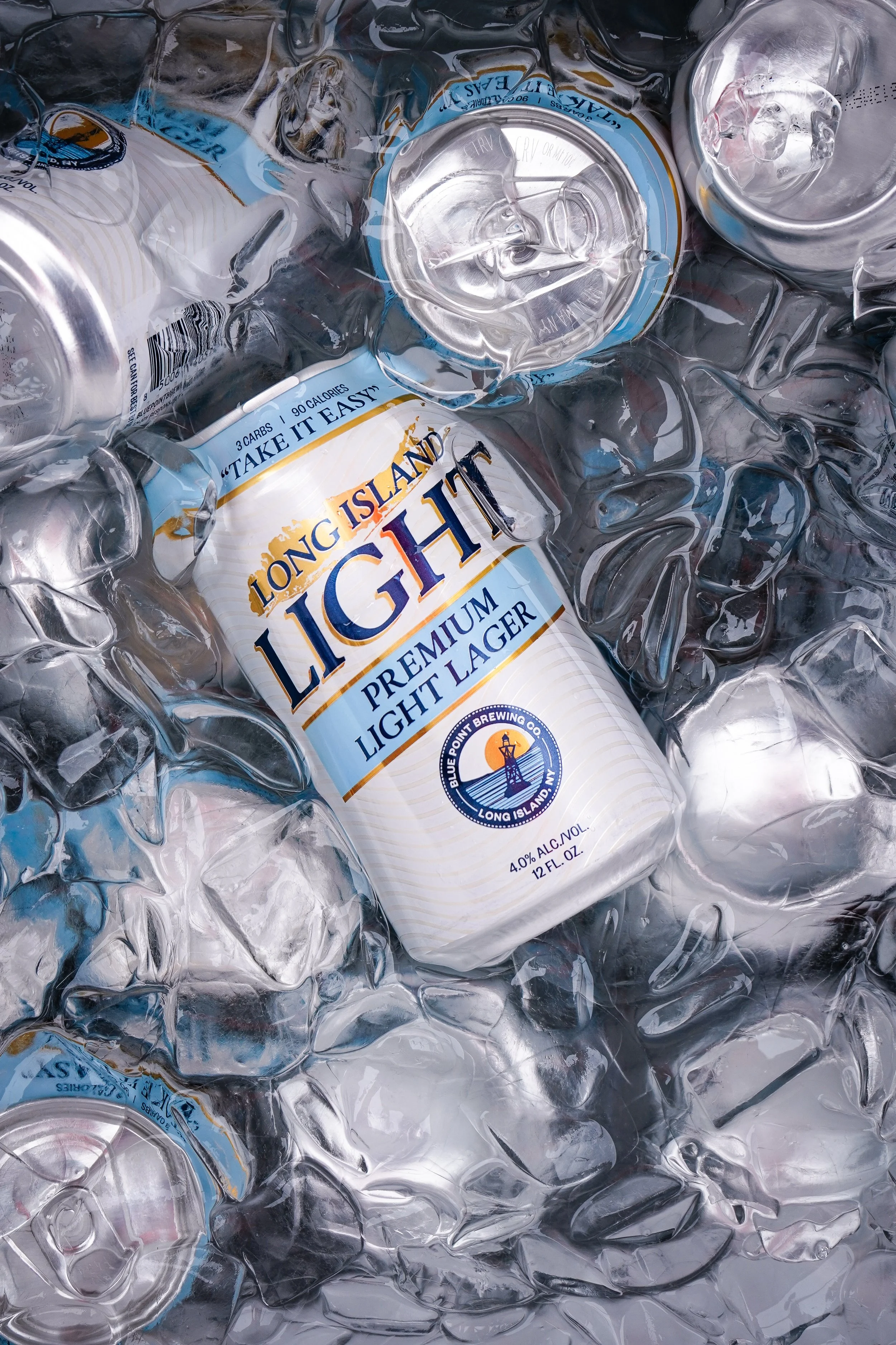 A collection of crushed aluminum cans, including a Long Island Light beer can, surrounded by ice cubes.