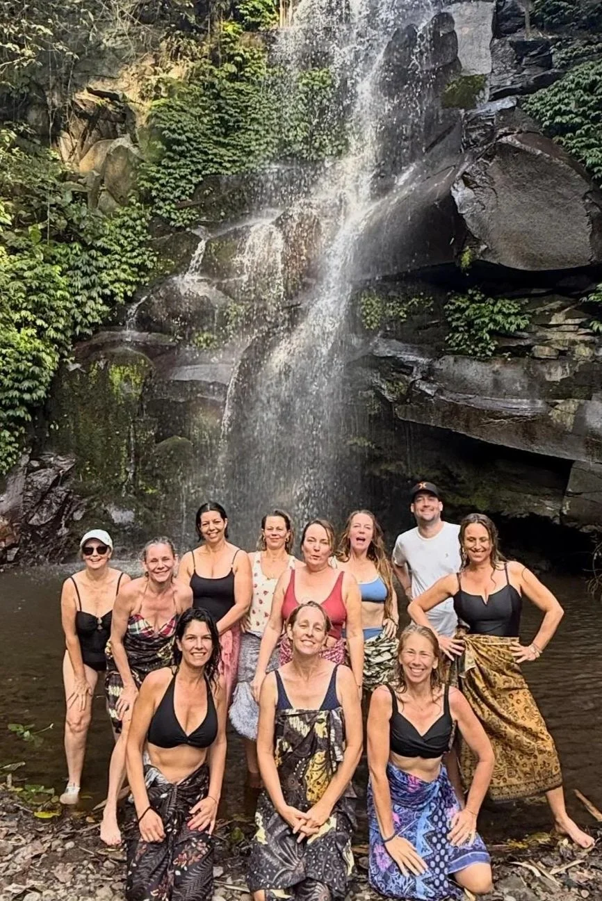 A group of people in swimwear behind a waterfall in a lush forest