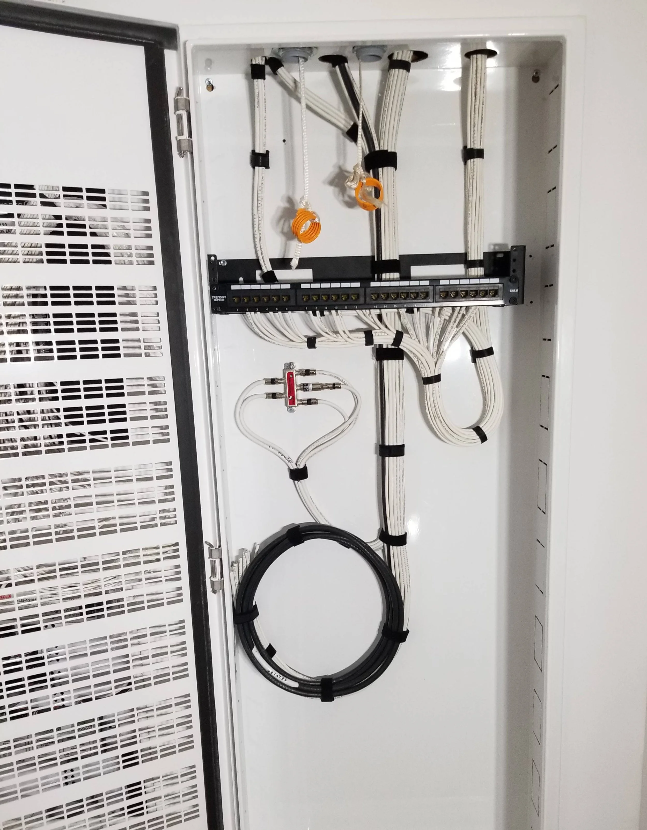 A neatly organized smart home data cabinet featuring cleanly dressed structured Cat6 cabling, coax distribution, and a fiber optic service loop, installed by the low-voltage experts at Koncept Electric.