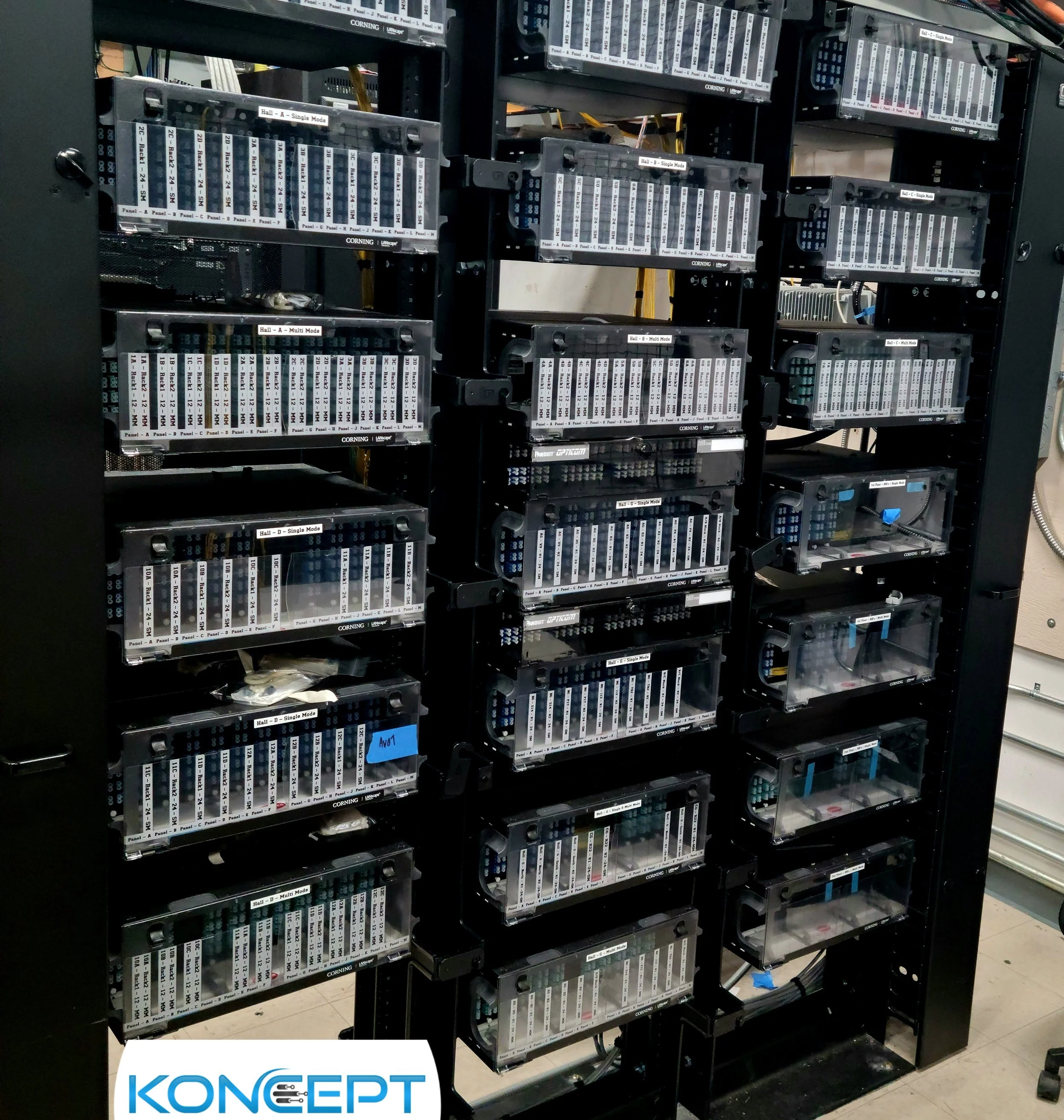 Three MDF data racks fully populated with terminated single-mode and multi-mode fiber optic cables, featuring precise 24-strand bulkhead connections installed by Koncept Electric in Nevada.