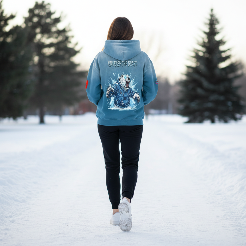 Person walking away in a snowy park, wearing a blue hoodie with a graphic of a bear and the text 'Unleash the Beast' on the back.