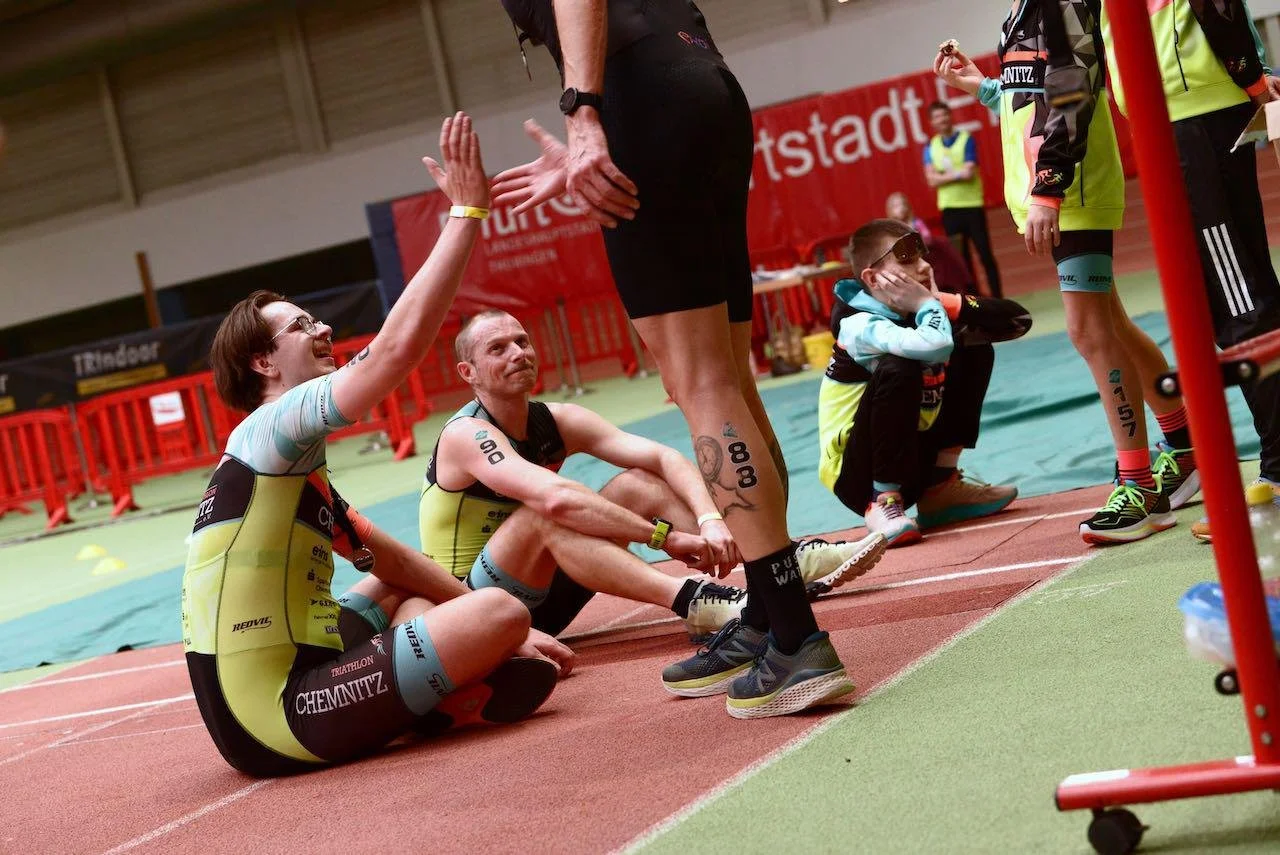 riathleten nach dem Zieleinlauf beim TRIndoor Chemnitz — erschöpft, glücklich, High-Five