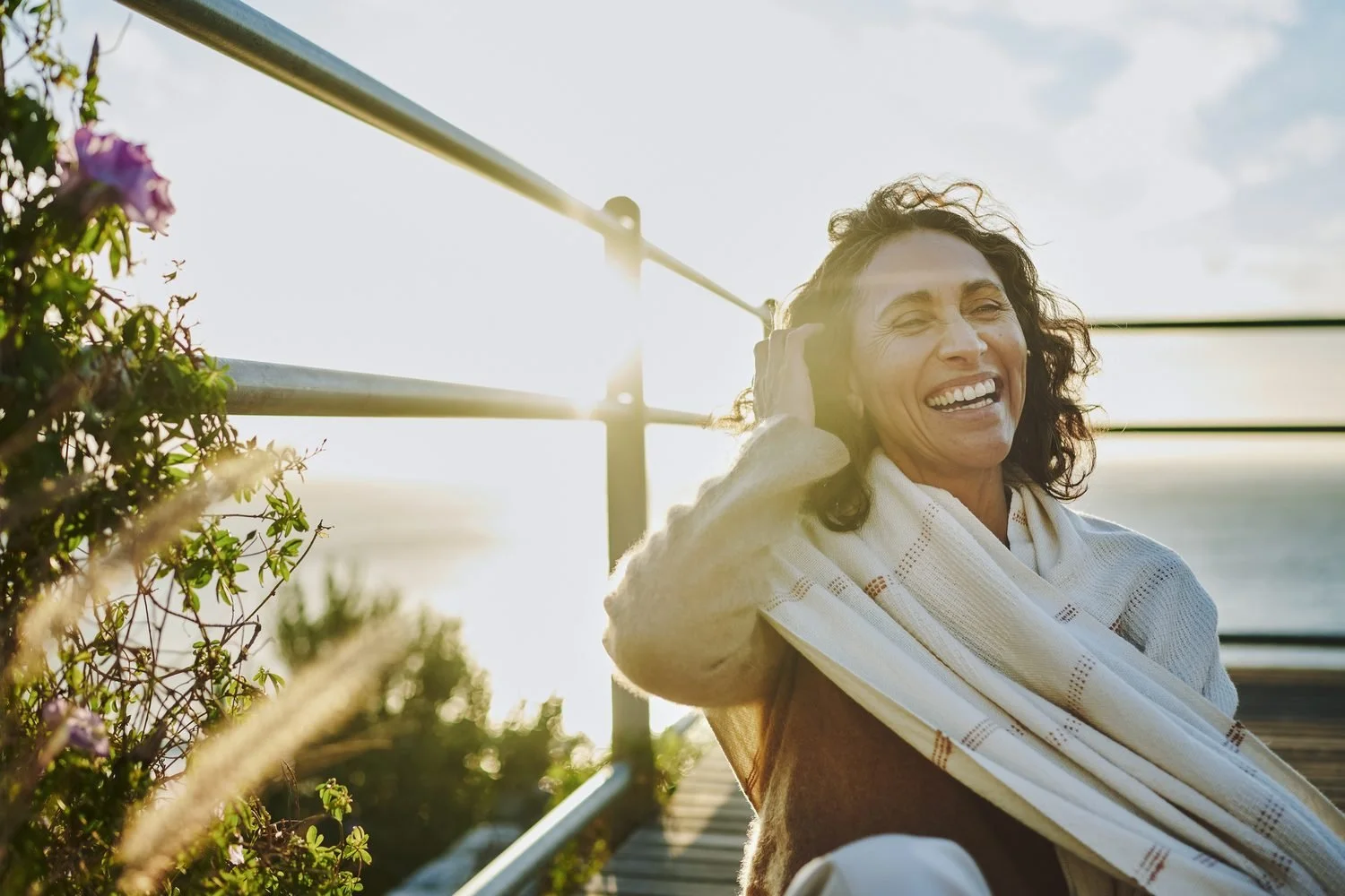 Woman laughing warmly outdoors, wrapped in a soft scarf