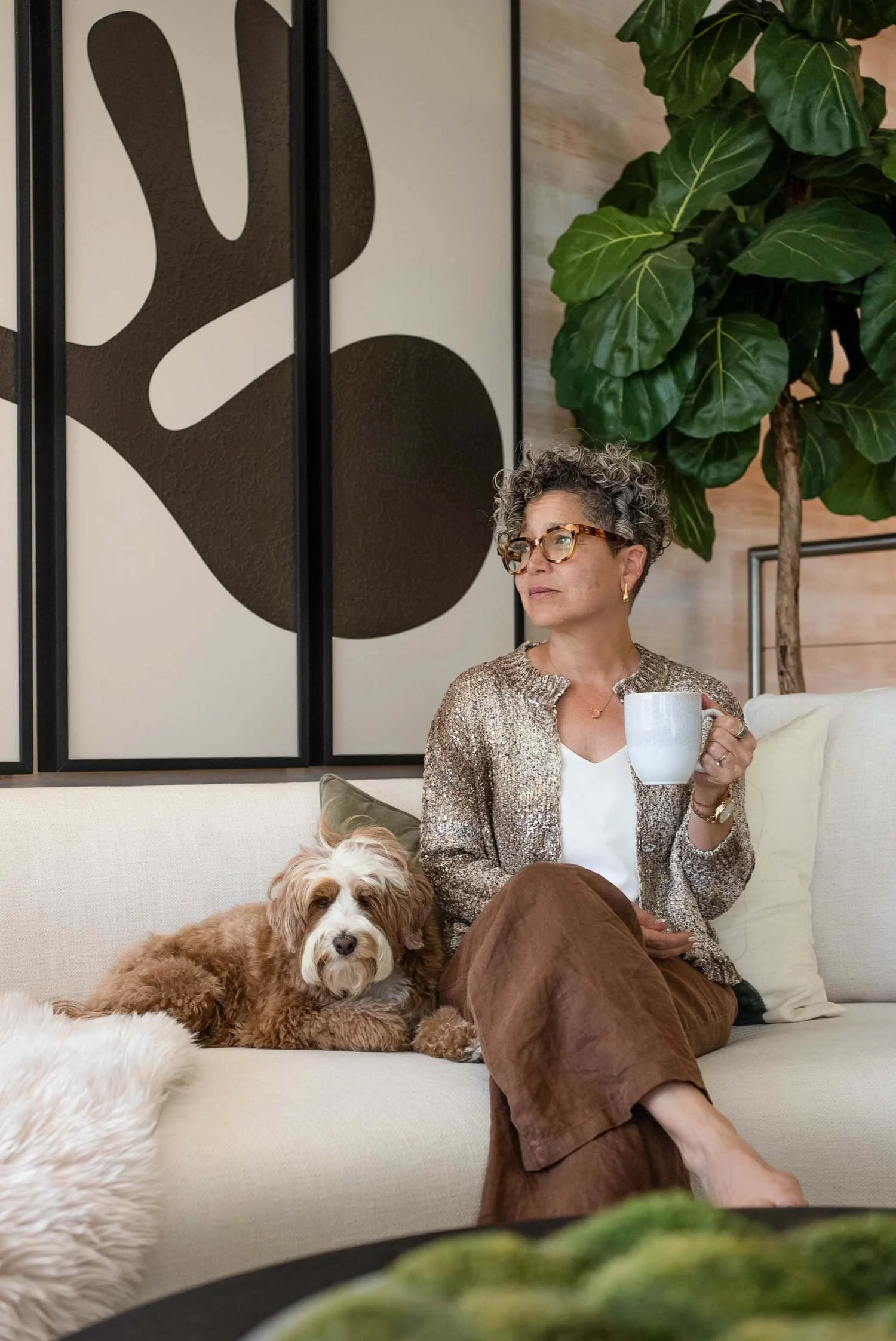 Kerry Ann sitting on her couch with her dog, drinking a cup of tea