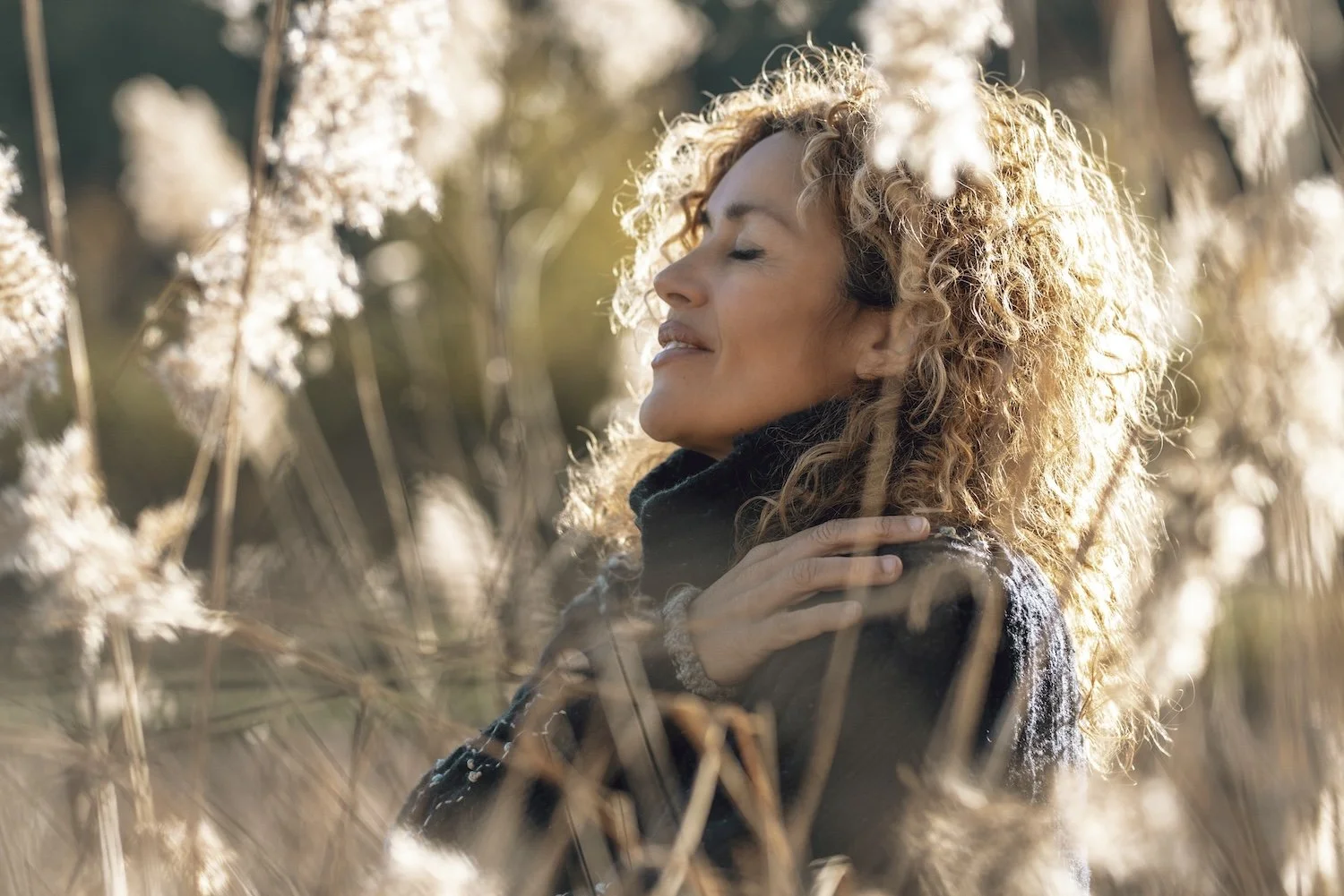 Woman pausing in sunlight, with hand over heart