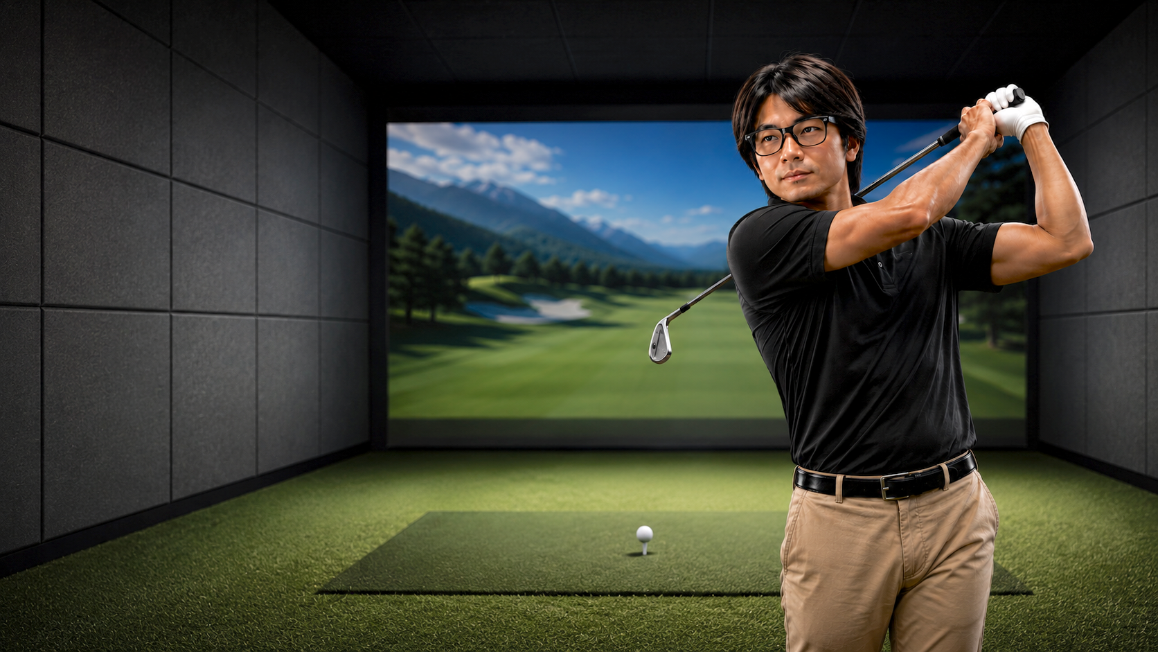 Man swinging a golf club in an indoor golf simulator with a scenic outdoor golf course displayed on the screen behind him.