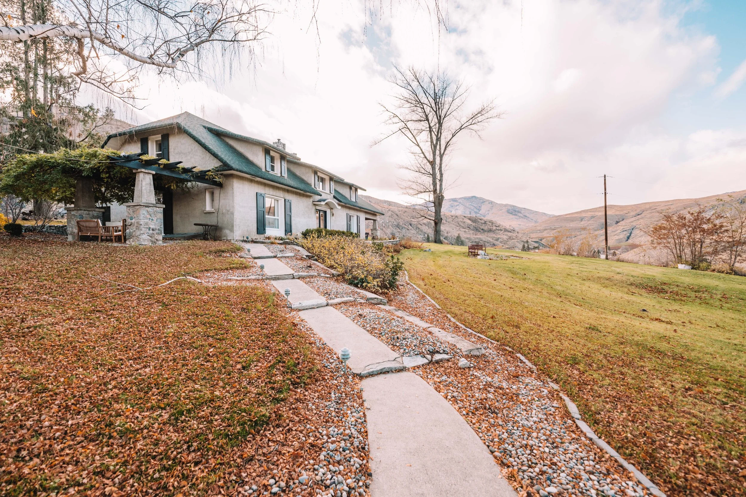 A view of the front of Cooper Creek Manor during October. The pathway is lightly covered in amber leaves on a cloudy day.