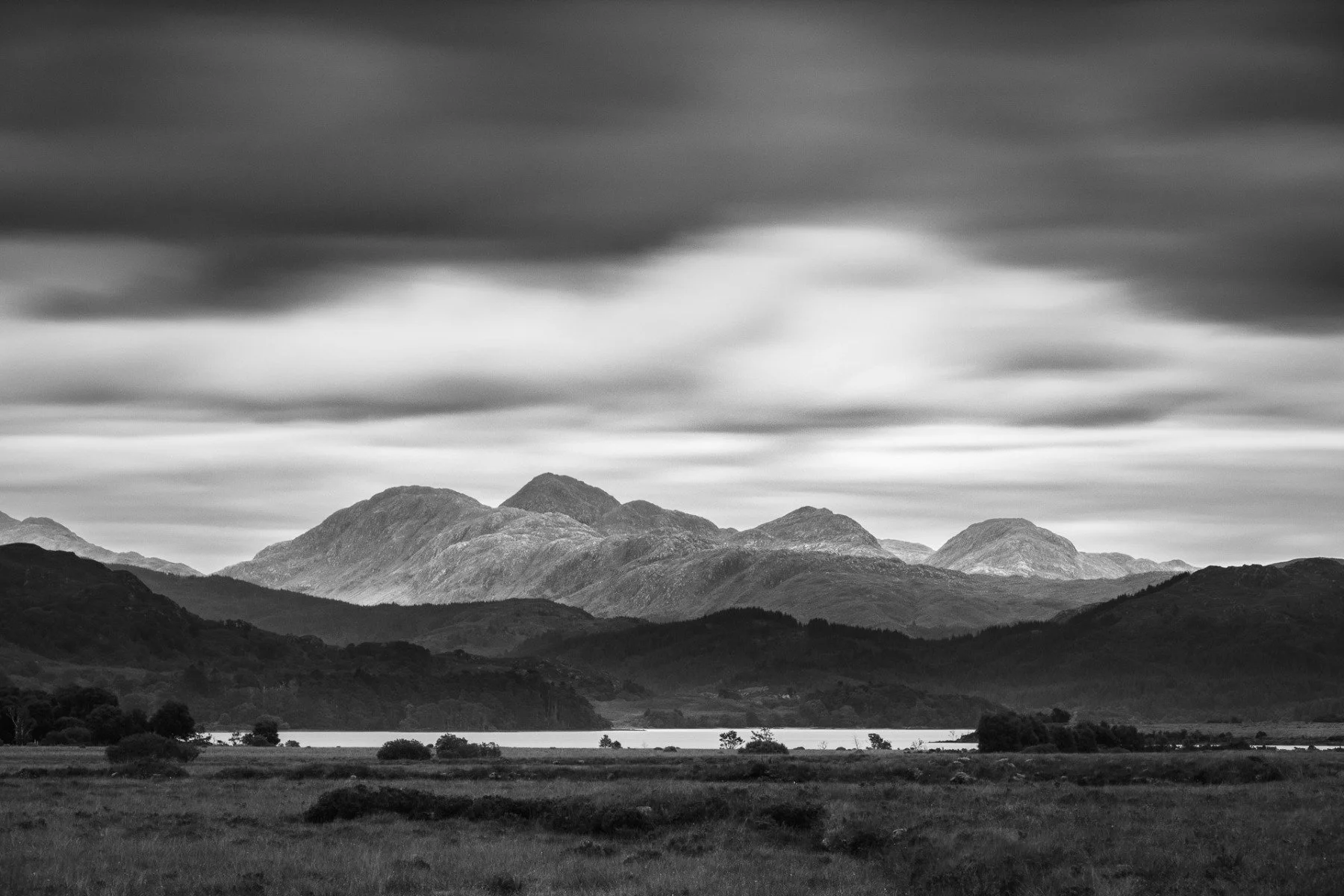 Long exposure black and white image of the mountain peaks of Druim Garbh, Sgùrr Dhomhnuill, Sgùrr na h-Ighinn and Sgùrr a’ Chaorainn in Ardgour viewed over Loch Shiel from Cnoc Breac | Mingarry Park Moidart Scotland | Steven Marshall Photography