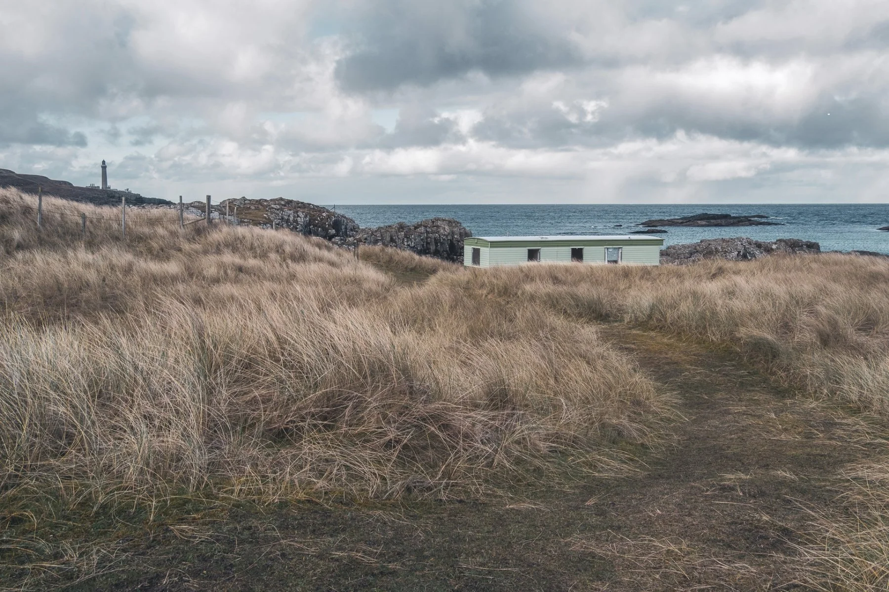 A static caravan amongst the sand dunes and marram grass at Port na Carraidh (Bay MacNeil) with the sea and Ardnamurchan Lighthouse in the background| Ardnamurchan Scotland | Steven Marshall Photography