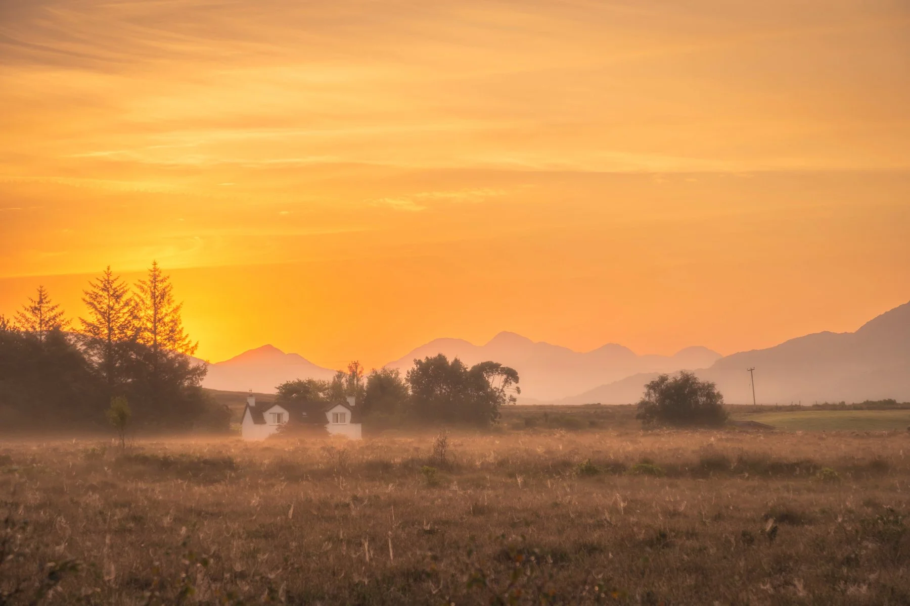 A golden sunrise over at cottage on a misty morning at Moss near Acharacle with the hills of Ardgour in the distance | Moidart Scotland | Steven Marshall Photography