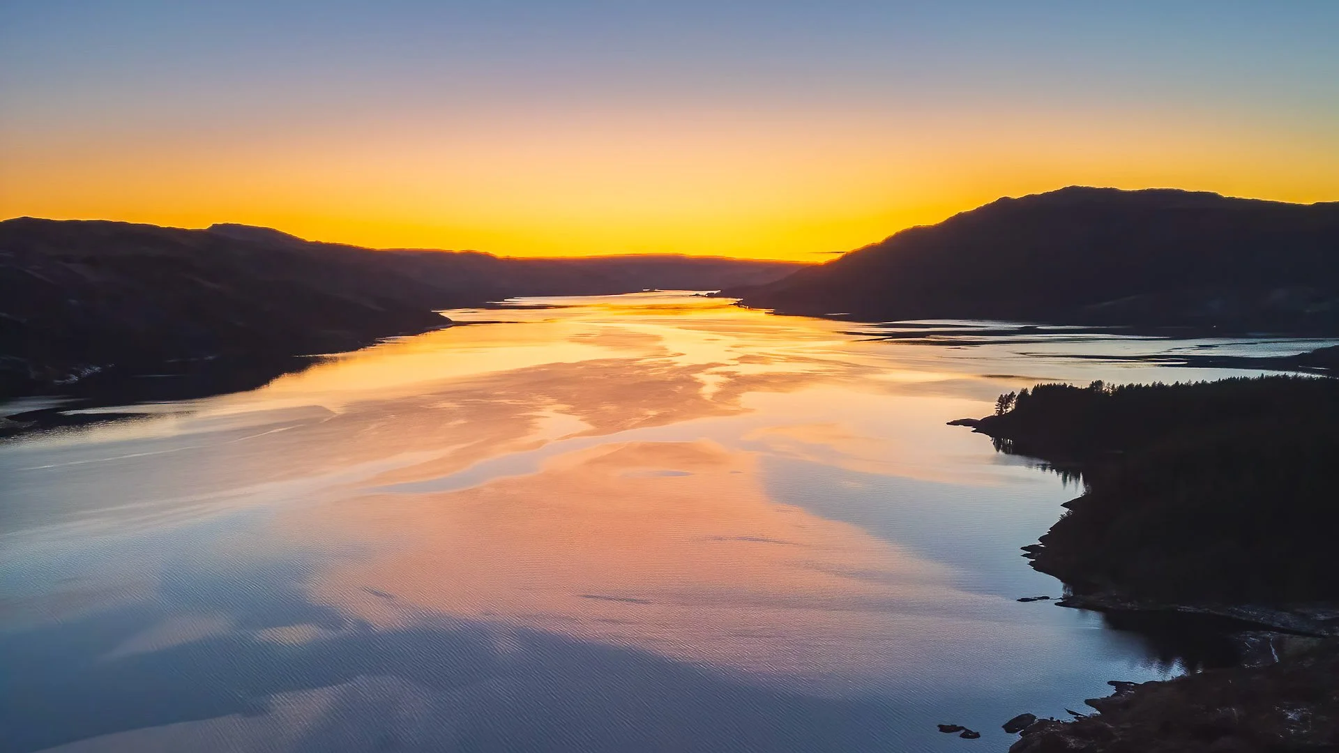 A winter sunset with a golden glow against a silhouette of the hills surrounding the sea loch at Resipole | Loch Sunart Scotland | Steven Marshall Photography