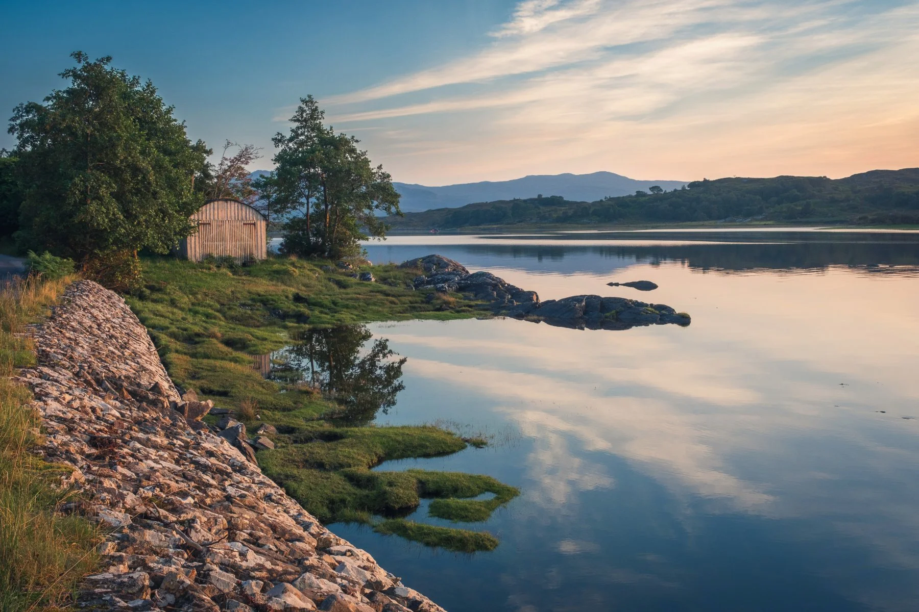 The warm light of sunset falling on a boathouse beside the River Shiel at Dorlin | Moidart Scotland | Steven Marshall Photography