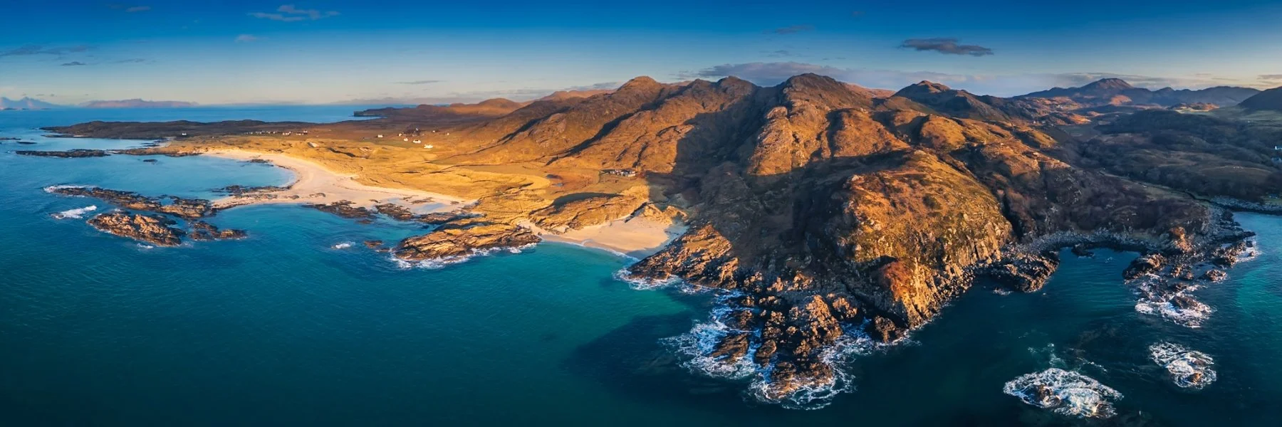 A drone view of the beach at Sanna under a blue sky with late afternoon sunshine falling on the south facing slopes of Meall Sanna | Ardnamurchan Scotland | Steven Marshall Photography