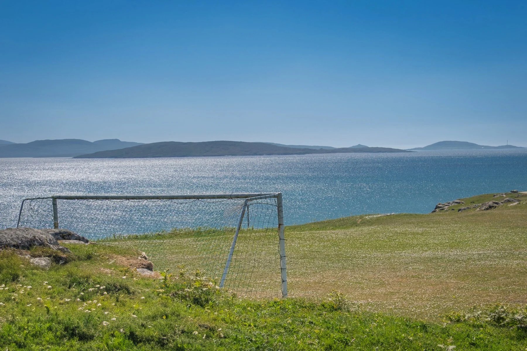 Goal posts at one end of Eriskay Football Club’s football pitch with a blue sky and sea in the background | Outer Hebrides Scotland | Steven Marshall Photography