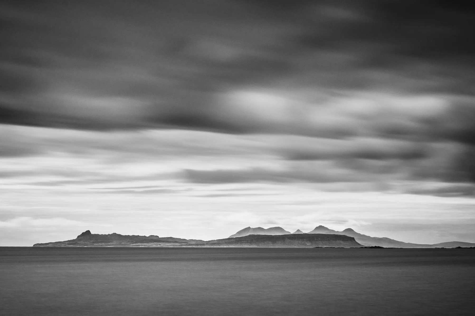 Long exposure black and white image of the Small Isles of Eigg and Rùm viewed over the sea from Rubh a' Chairn Mhoir | Glenuig Moidart Scotland | Steven Marshall Photography