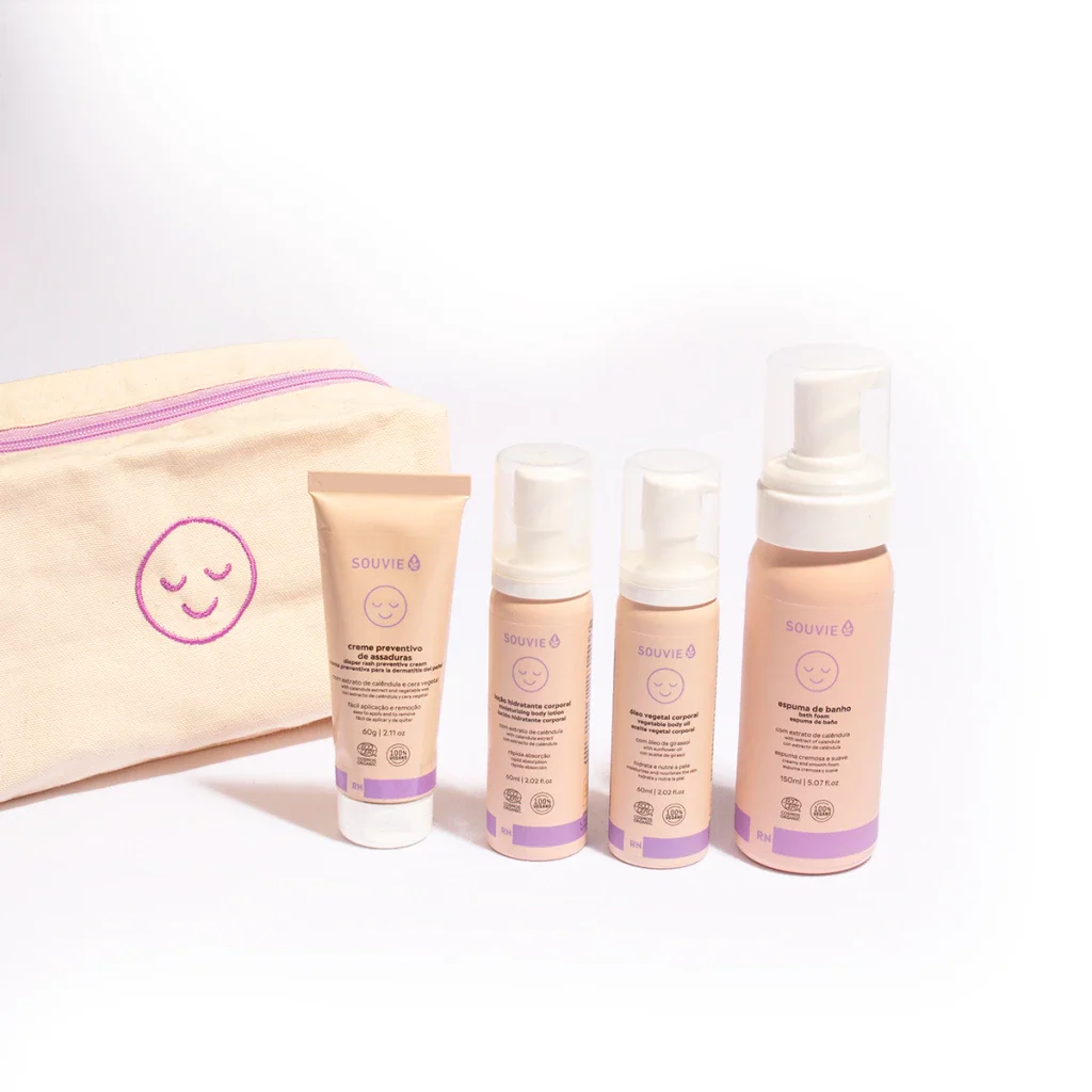 Kit de soins de la peau avec une trousse beige ornée d'un visage souriant, contenant des produits de soin visage et corps de la marque Souvie, tels que une crème préventive, un gel hydratant corporel, un gel végétal corporel et une mousse de bain.