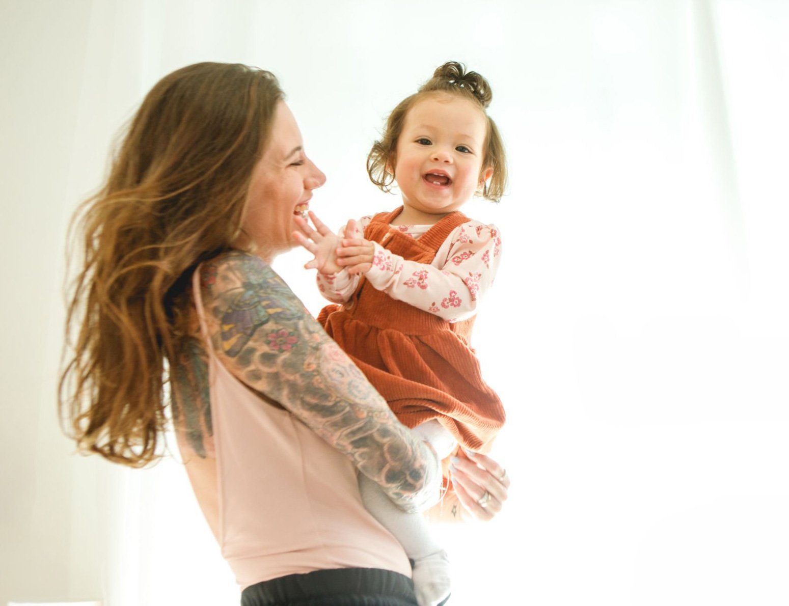 Woman smiling in a bright room, representing inclusive online mental health care for mothers across Australia