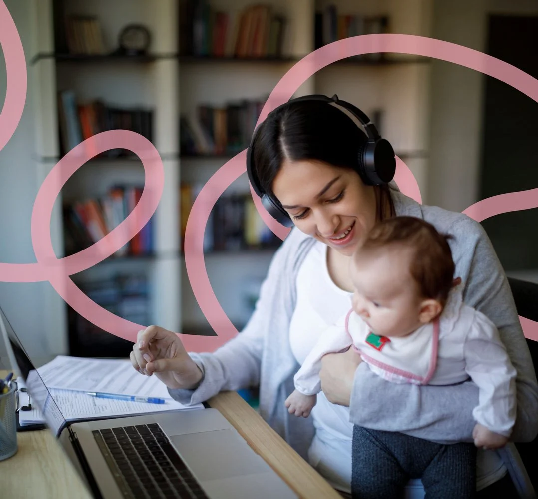 Woman with headphones holding an infant at her desk during a virtual therapy session with an online perinatal psychologist
