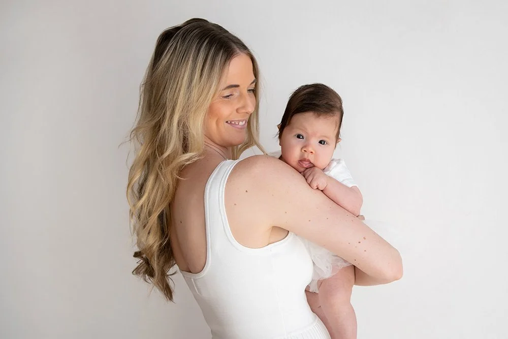 Smiling mother holding her newborn baby in her arms, representing postpartum therapy and early motherhood support