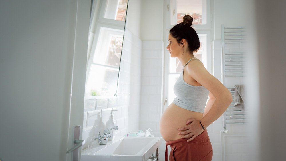Woman looking at her pregnant reflection, illustrating emotional support during the journey of pregnancy