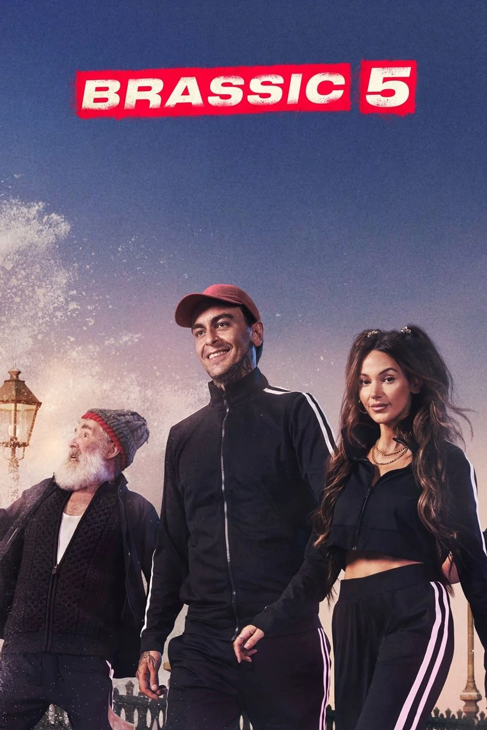 Poster for the movie 'Brassic 5' showing three characters outdoors during sunset, with a man wearing a red cap and black tracksuit, a woman with long wavy hair in a black tracksuit, and an older man with a gray beard and knitted hat, with a streetlam