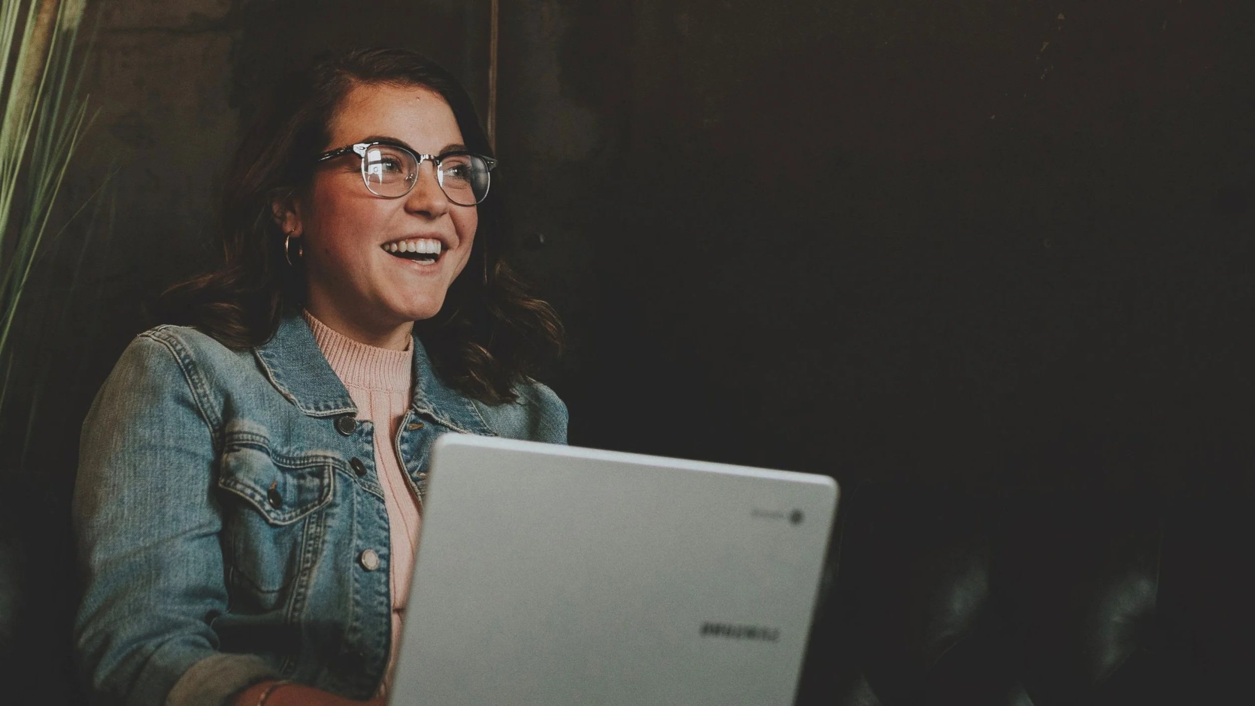 A smiling woman accessing Kyria Network's leadership resources on her laptop.