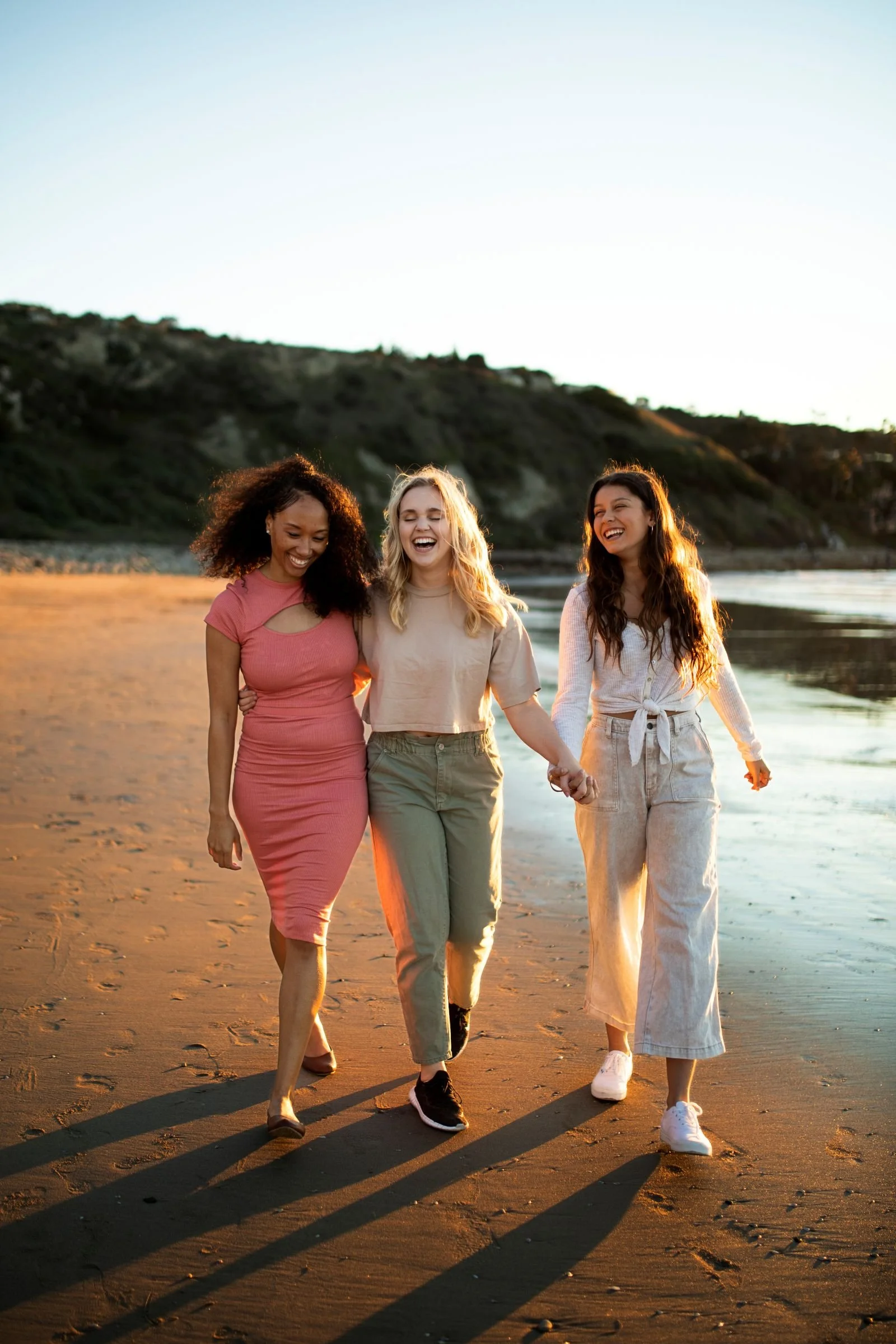 Women leaders smiling and walking on the beach as the sun goes down.