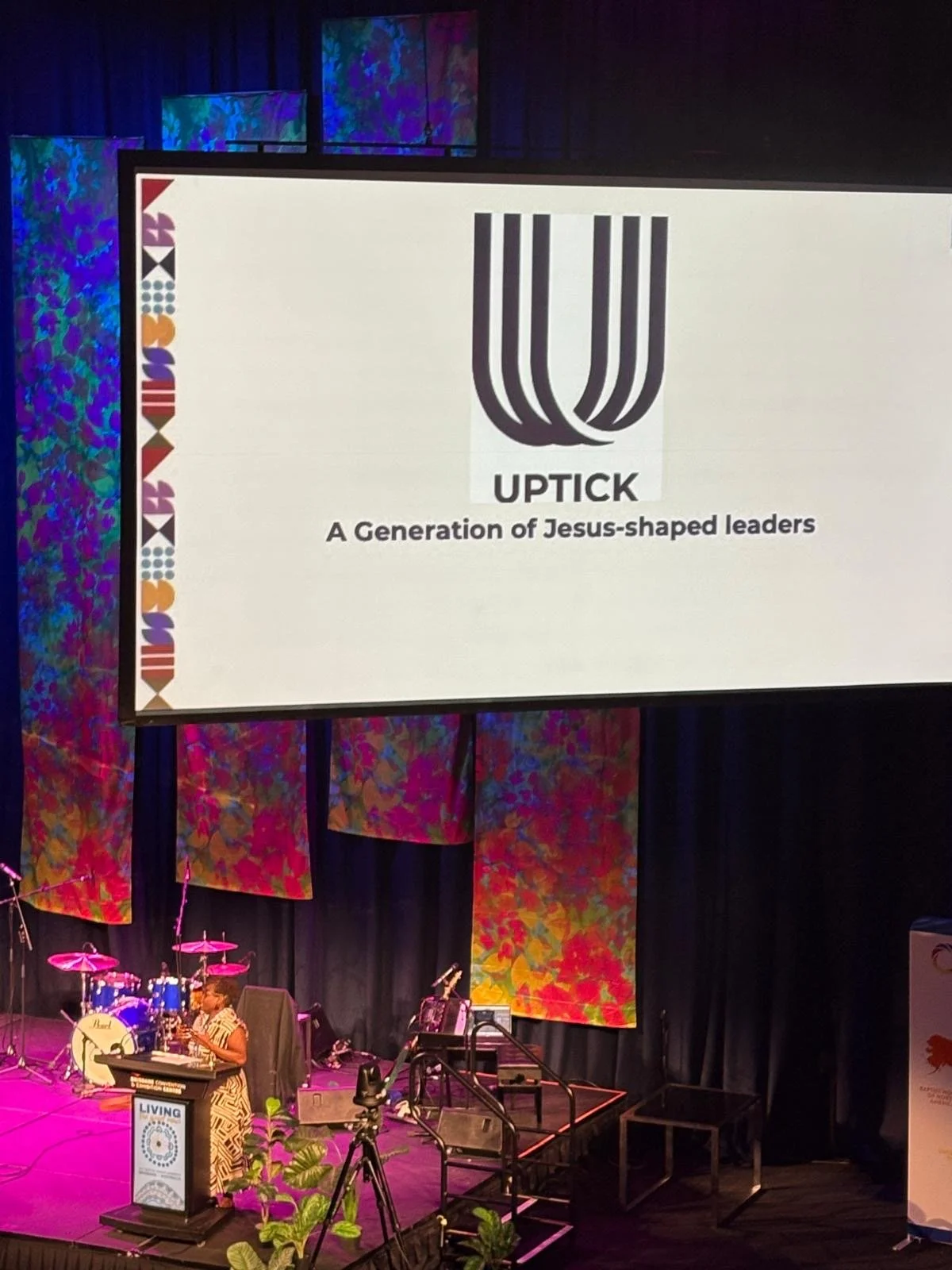 A woman leader speaking from stage at an Uptick Global Leader's Summit.