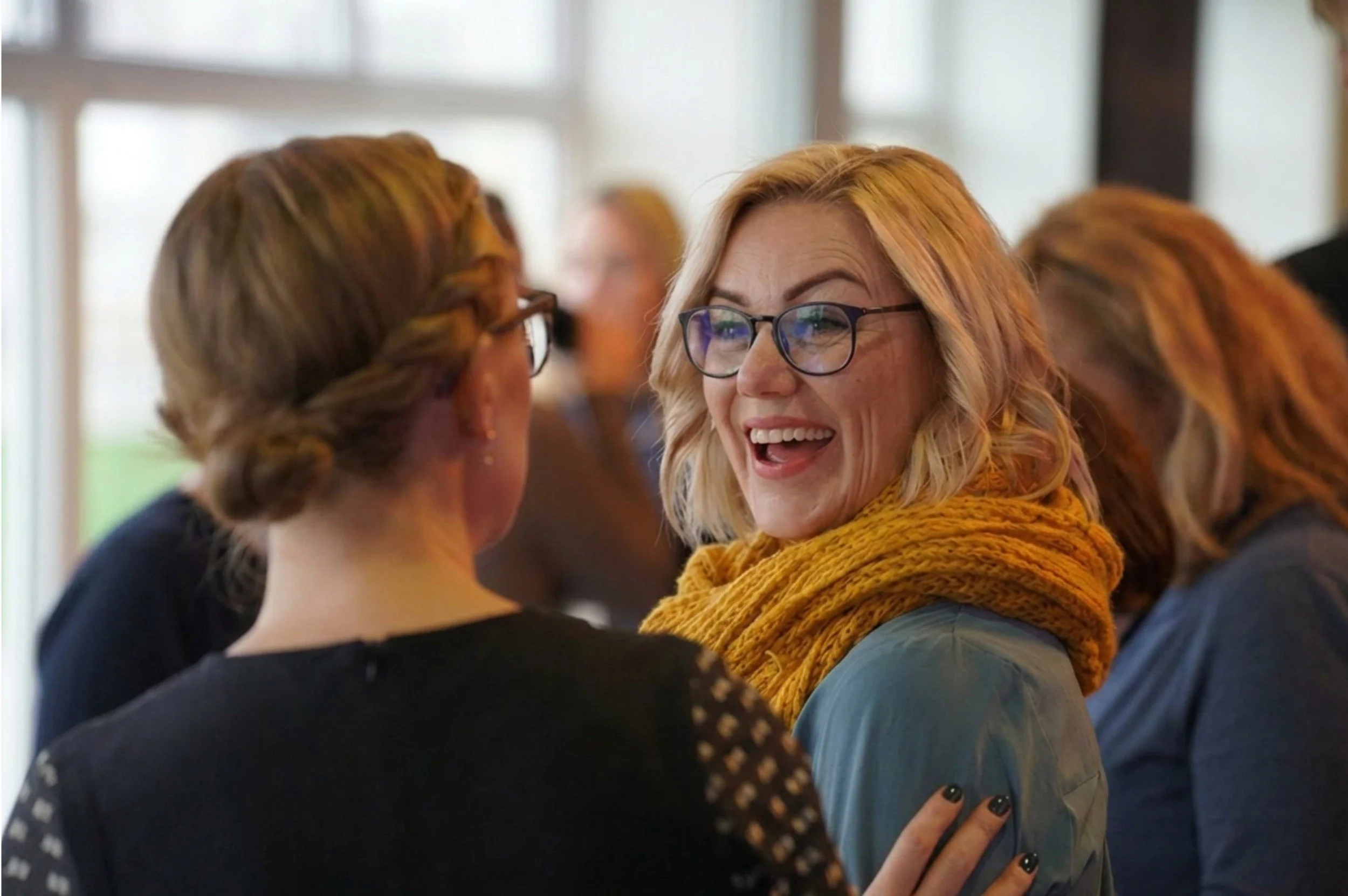 Women smiling and talking at a women in leadership event.