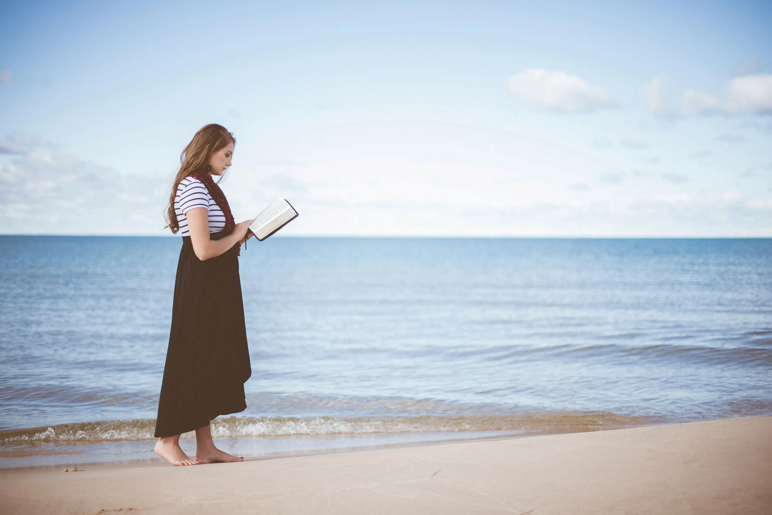 A woman reading a bible on the beach