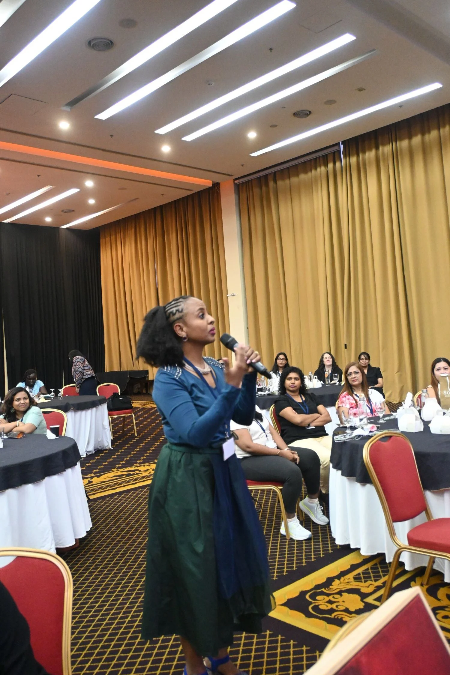 A woman sharing her experiences in leadership devlopment at a conference.